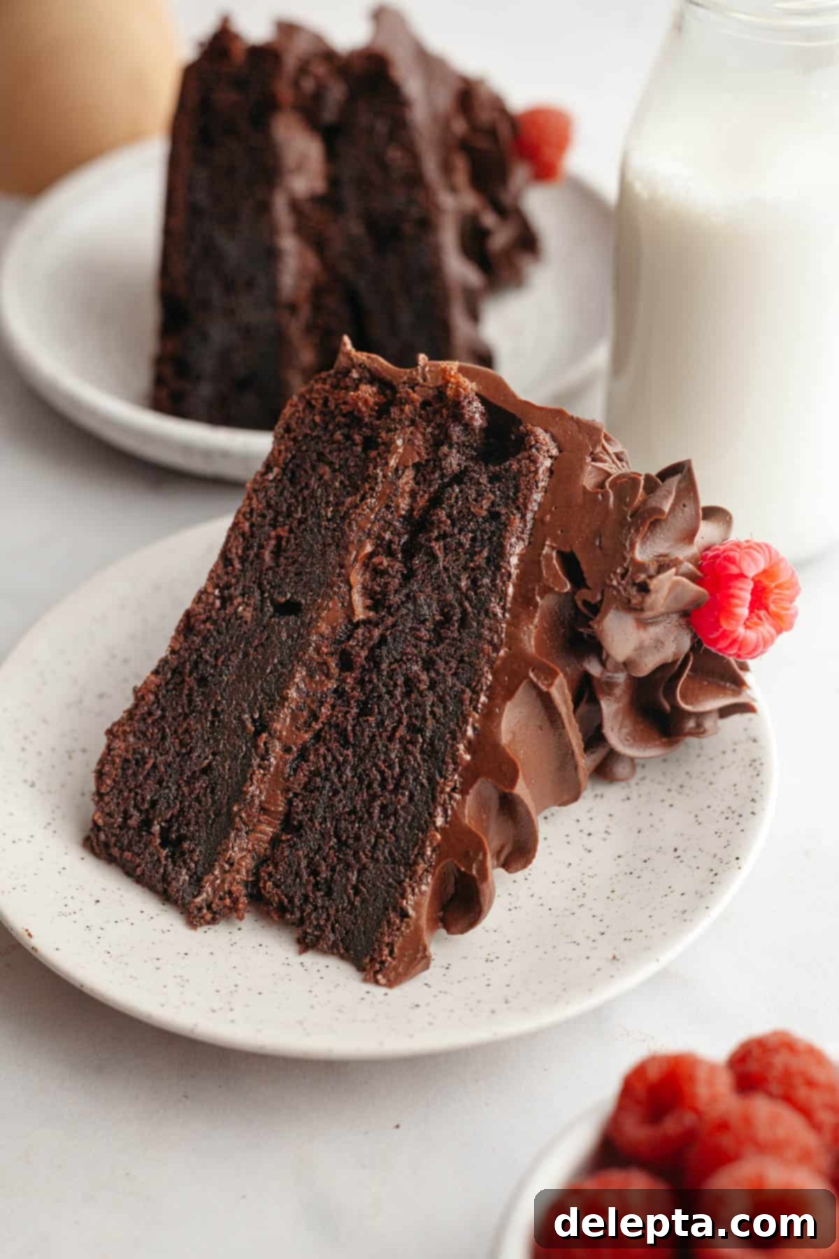 Moist and Easy Chocolate Cake with Decadent Chocolate Ganache 13 A single, delectable slice of chocolate cake with creamy ganache, elegantly presented on a small white plate, ready to be enjoyed.