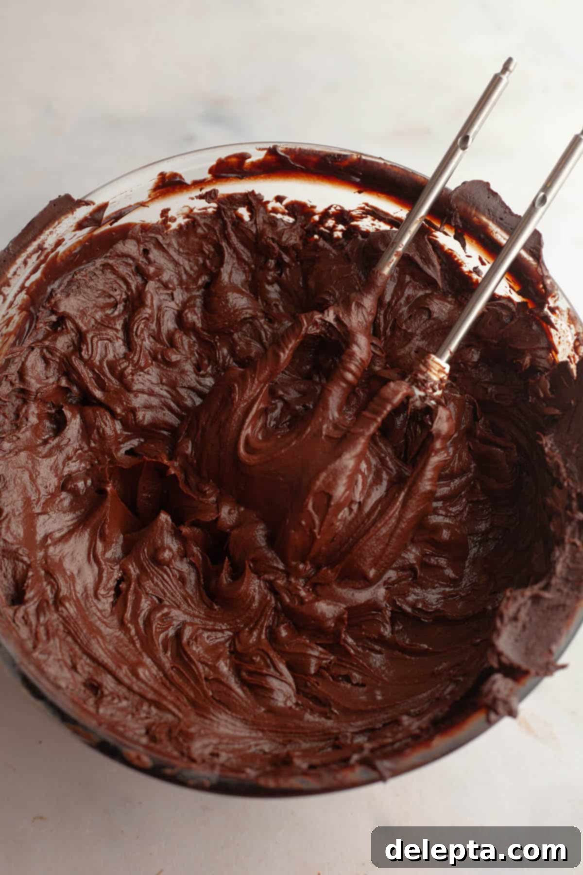 Moist and Easy Chocolate Cake with Decadent Chocolate Ganache 10 Smooth, dark chocolate ganache resting in a large glass bowl, showing its glossy texture as it cools and sets at room temperature.