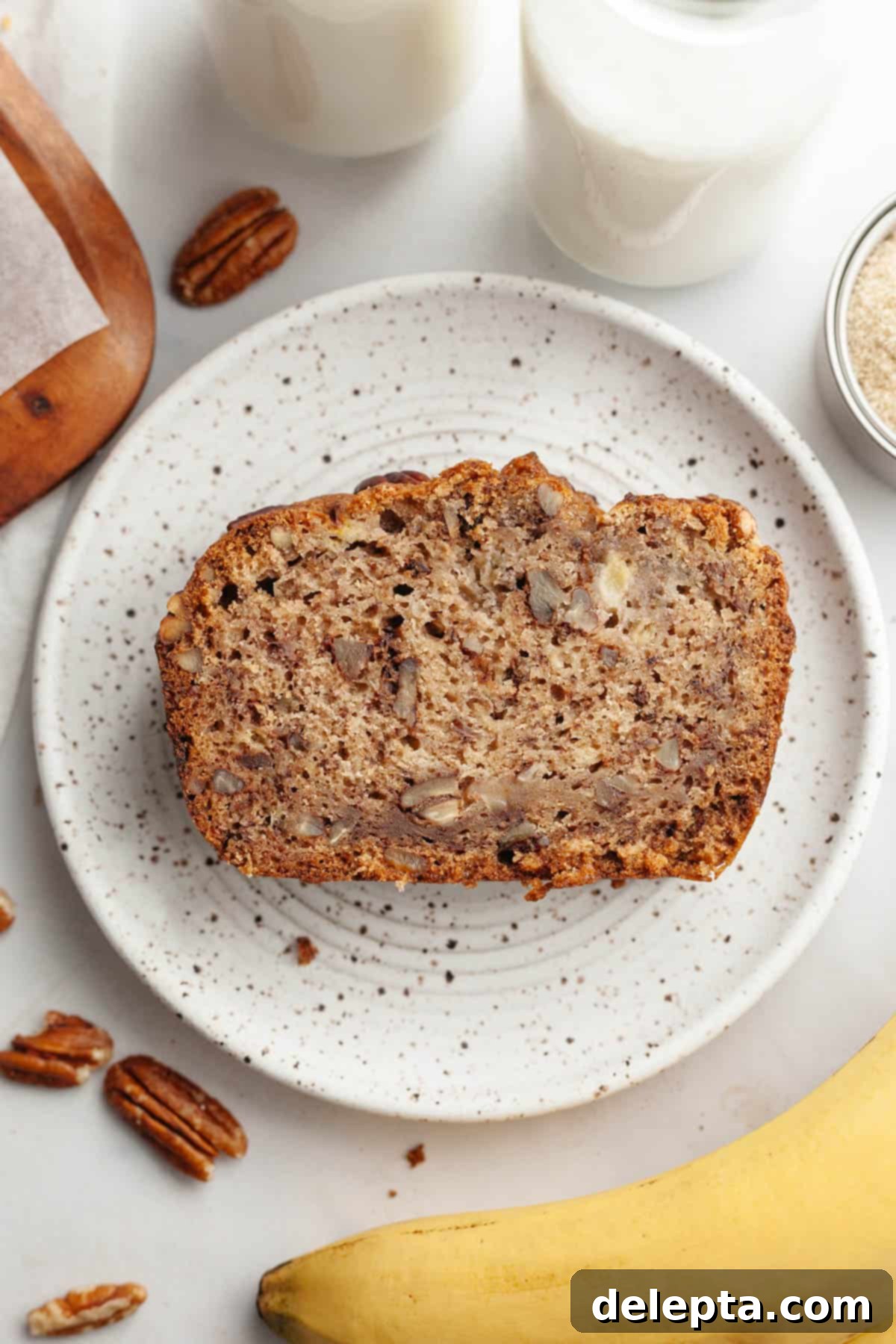 Decadent Brown Butter Cinnamon Pecan Banana Bread 11 A slice of banana bread with pecans on a small plate.