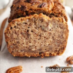 Decadent Brown Butter Cinnamon Pecan Banana Bread 12 A close up of a slice of pecan banana bread on parchment paper.