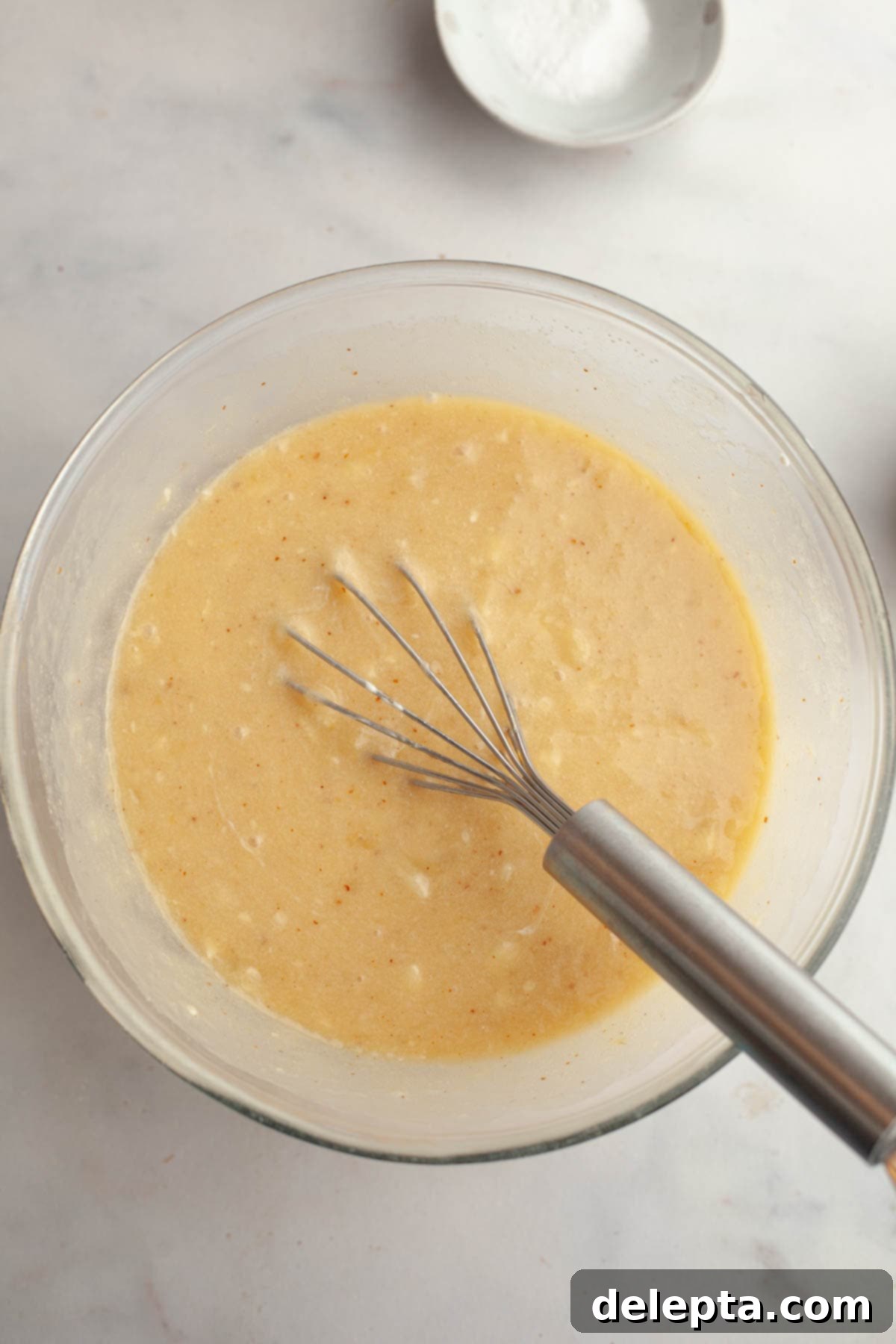 Decadent Brown Butter Cinnamon Pecan Banana Bread 5 Banana bread batter in a large glass mixing bowl with a whisk.