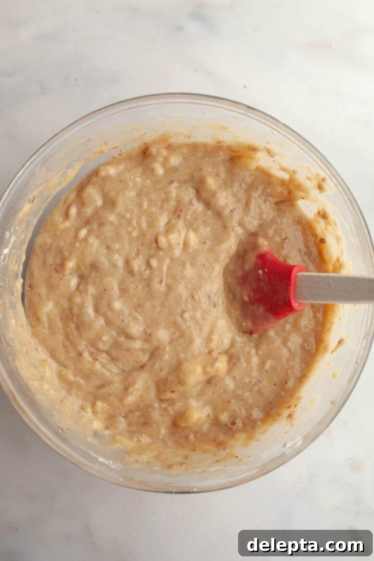 Decadent Brown Butter Cinnamon Pecan Banana Bread 6 Banana bread batter in a large glass mixing bowl with a rubber spatula.