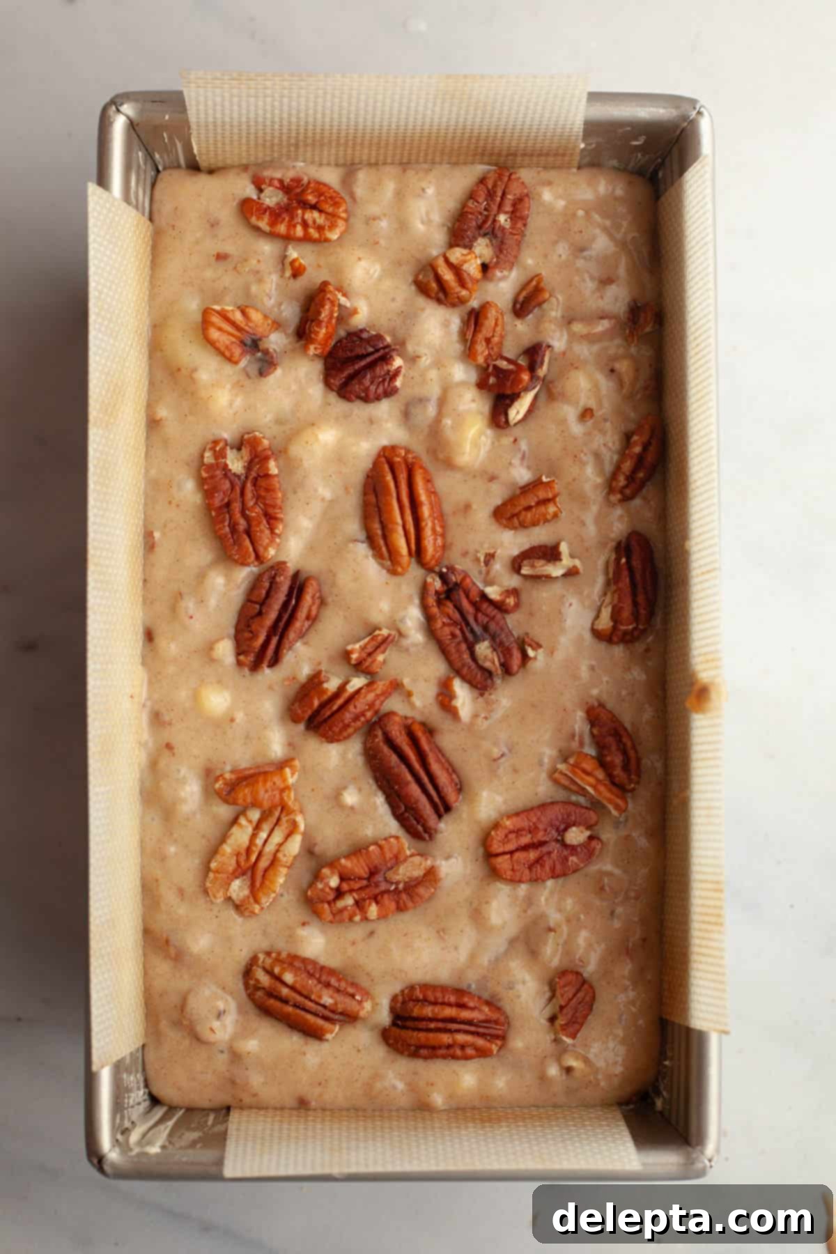 Decadent Brown Butter Cinnamon Pecan Banana Bread 8 Unbaked banana bread with pecans in a loaf pan.