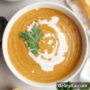 Velvety Roasted Butternut Cauliflower Soup 10 A white soup bowl with butternut squash cauliflower soup, drizzled with cream and garnished with herbs.
