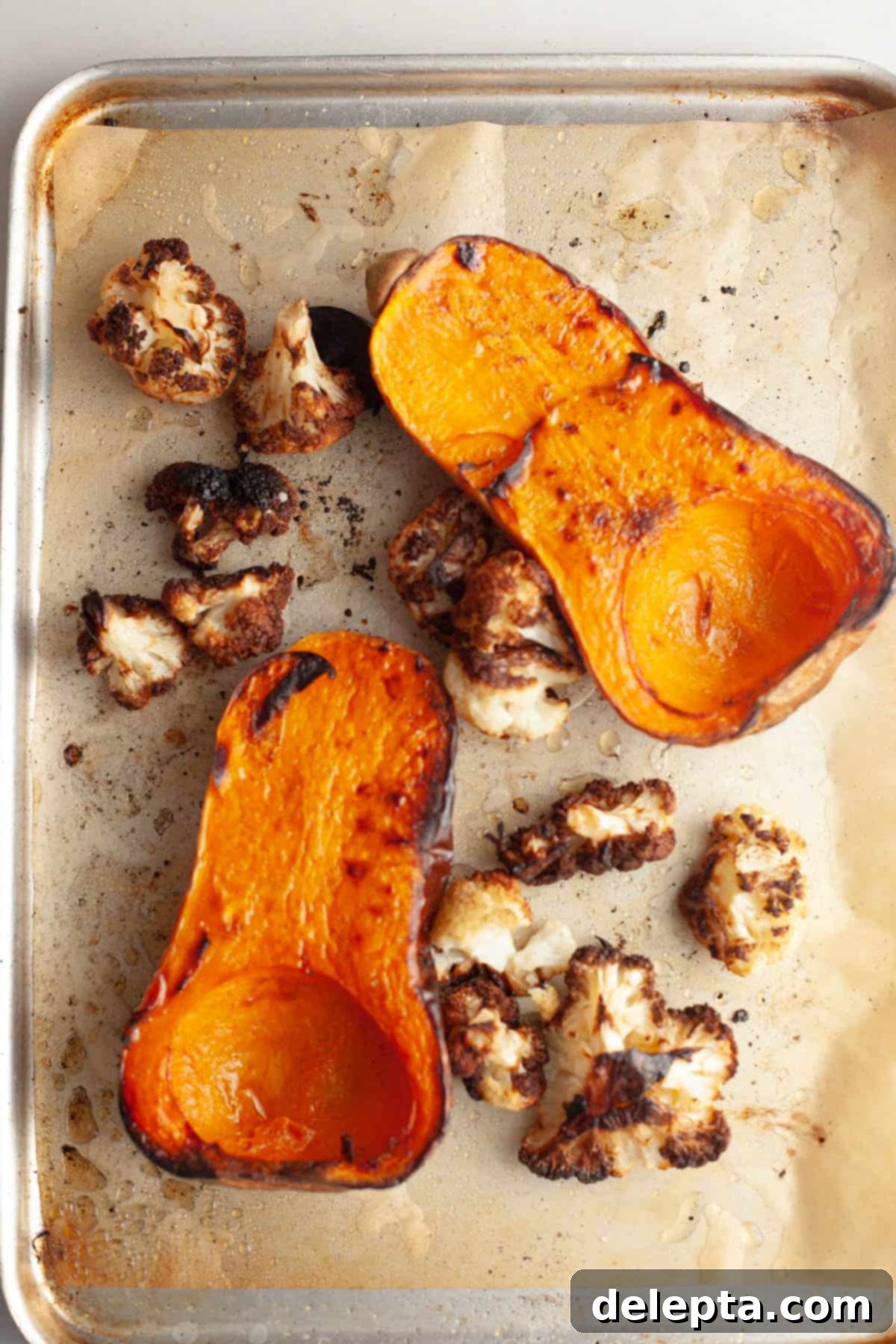 Velvety Roasted Butternut Cauliflower Soup 6 A sheet pan with roasted butternut squash cut in half and perfectly roasted cauliflower florets, showing their caramelized edges.
