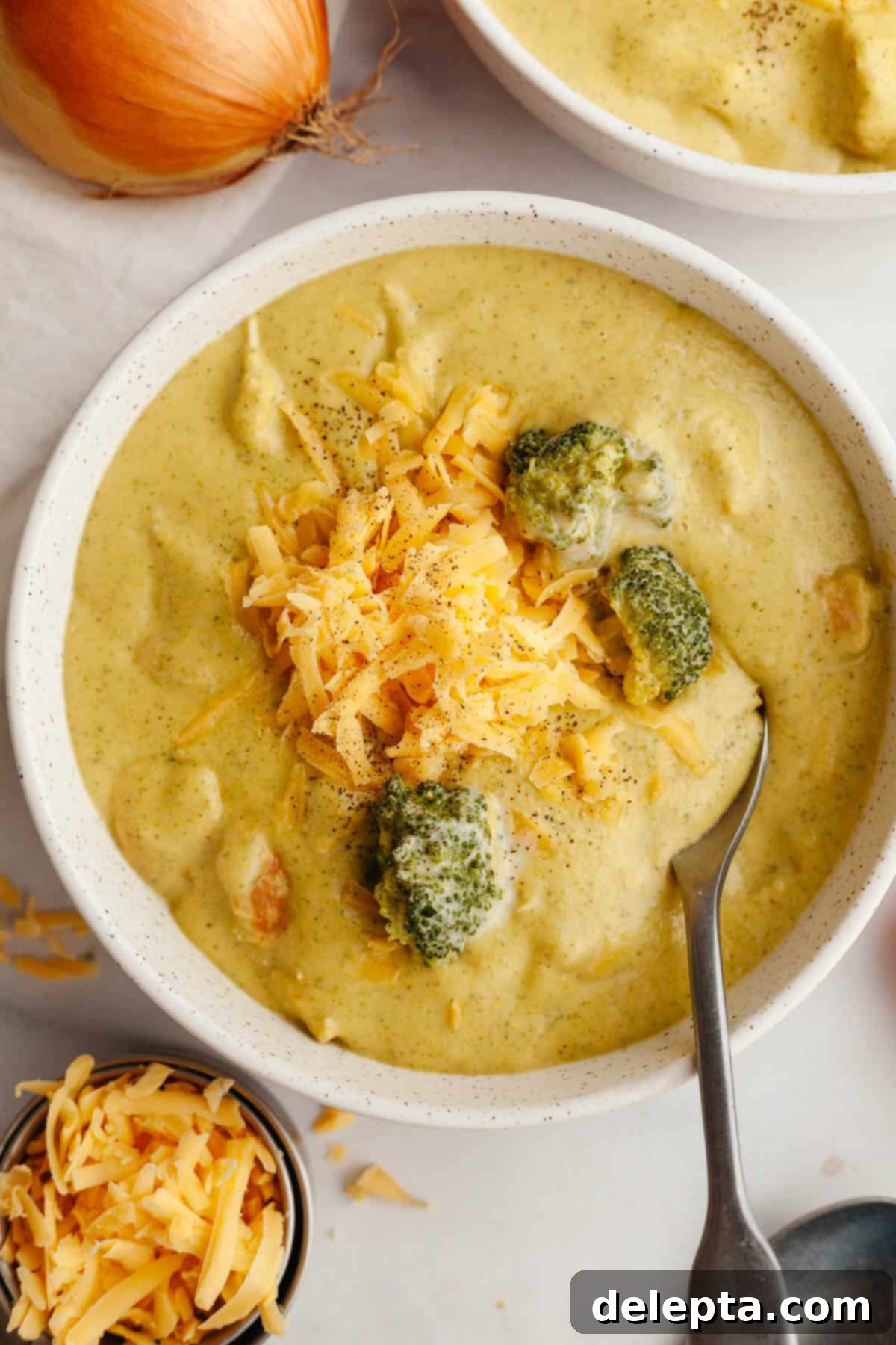 Velvety Chicken and Broccoli Cheddar Soup 2 A steaming bowl of homemade chicken and broccoli cheddar soup, generously topped with extra shredded cheddar cheese and a sprinkle of fresh parsley.