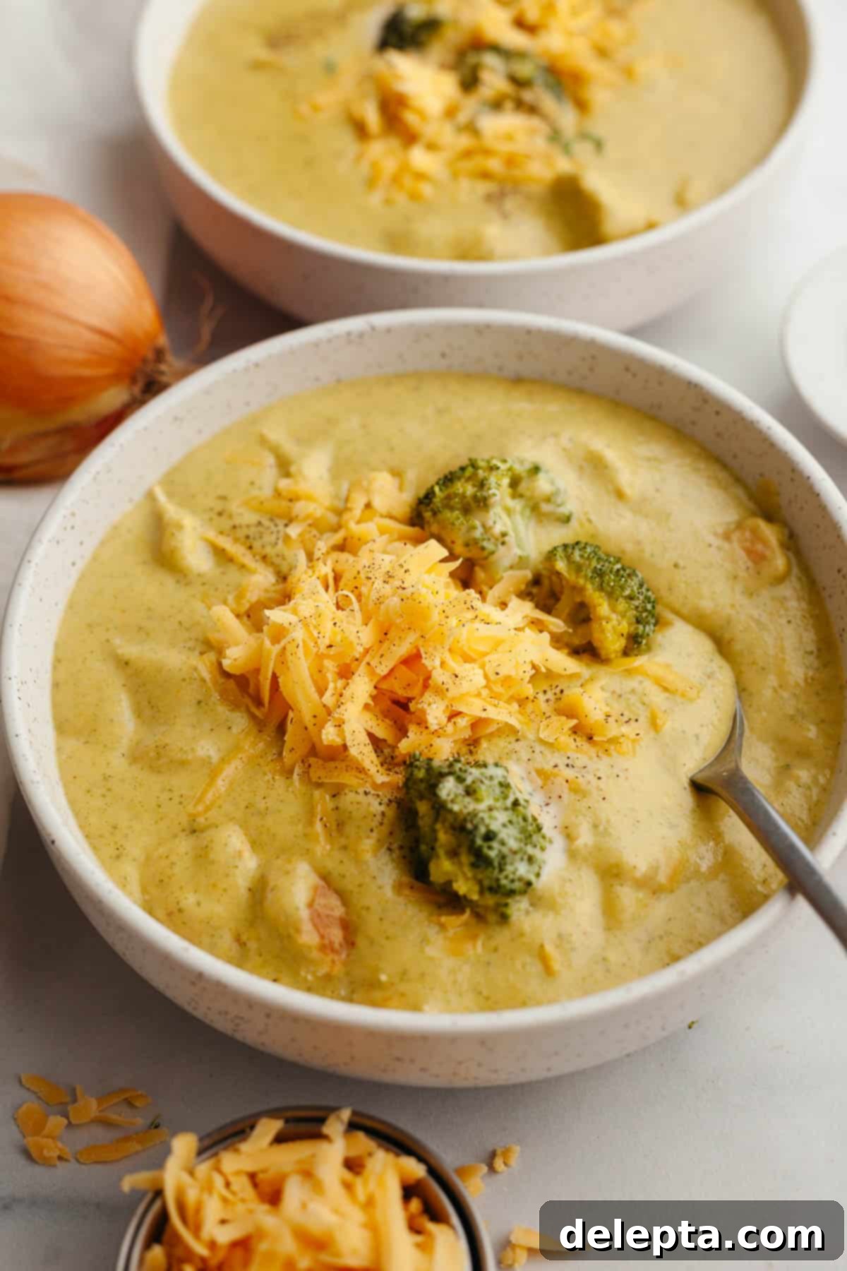 Velvety Chicken and Broccoli Cheddar Soup 13 Another enticing bowl of creamy chicken and broccoli cheddar soup, garnished with additional shredded cheese, viewed from a slightly different angle.