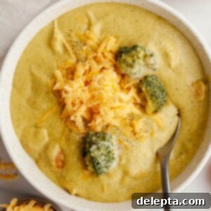 Velvety Chicken and Broccoli Cheddar Soup 14 A bowl of chicken and broccoli cheddar soup, topped with shredded cheddar cheese.
