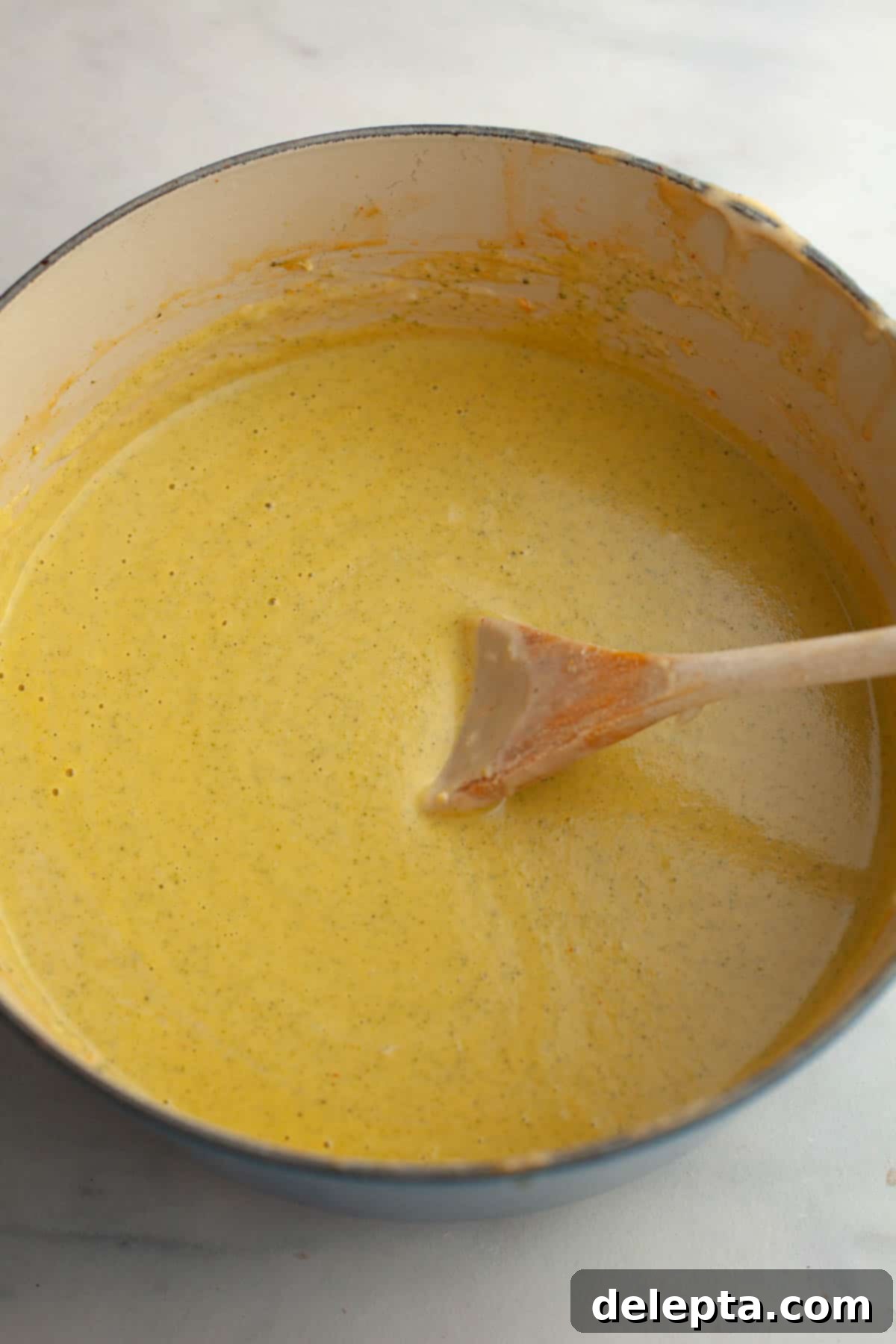 Velvety Chicken and Broccoli Cheddar Soup 9 A large pot of broccoli cheddar soup, being pureed with an immersion blender for a smooth texture.