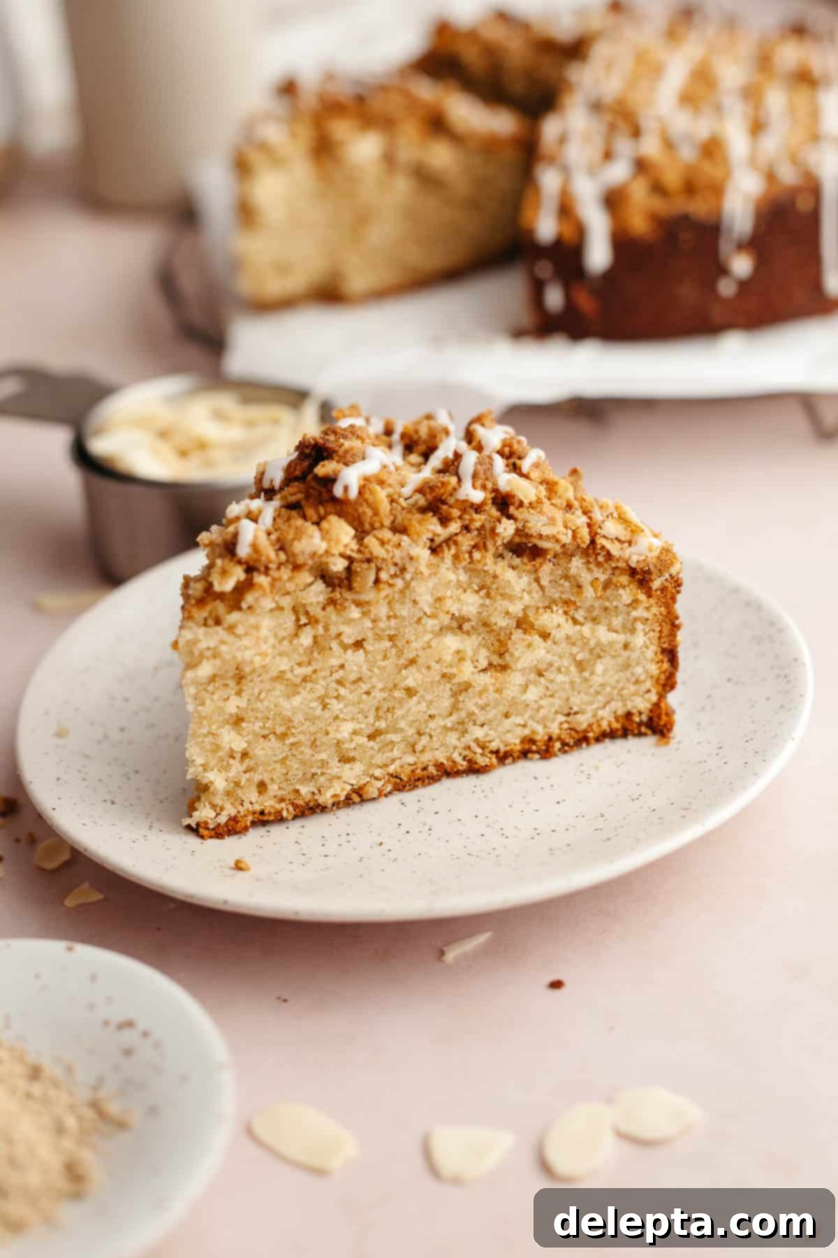 Irresistible Brown Butter Cardamom Almond Cake Recipe 2 A slice of cardamom almond cake on a small plate, drizzled with a glaze.