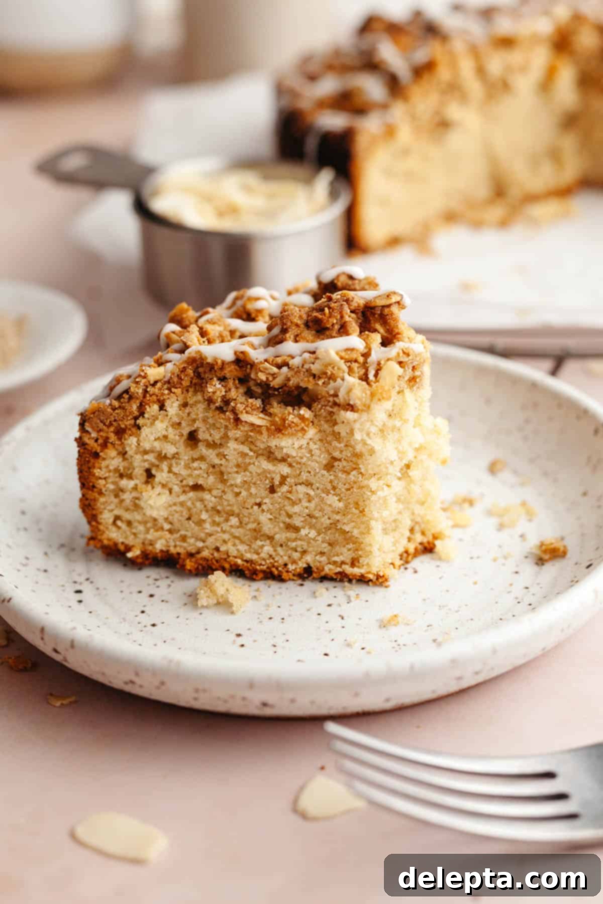 Irresistible Brown Butter Cardamom Almond Cake Recipe 11 A slice of almond cardamom cake on a plate, a bite has been taken out of it.