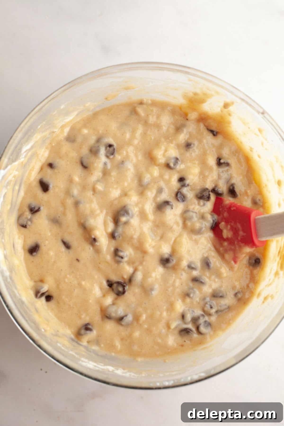 Bakery Style Jumbo Banana Chocolate Chip Muffins 7 Banana chocolate chip muffin batter in a bowl, ready to be scooped.