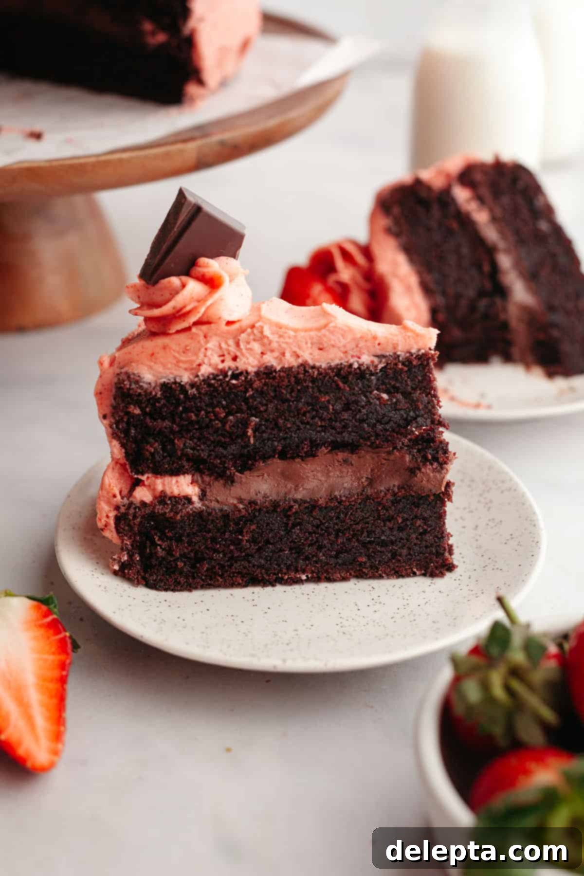 Decadent Chocolate Strawberry Dream Cake 2 A chocolate cake covered in strawberry frosting with chocolate filling on a small plate.