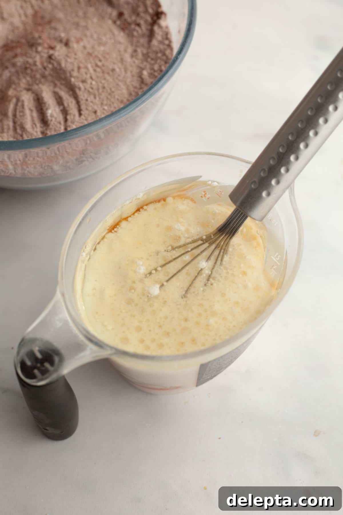 Decadent Chocolate Strawberry Dream Cake 5 A jug with a whisk and buttermilk and oil.
