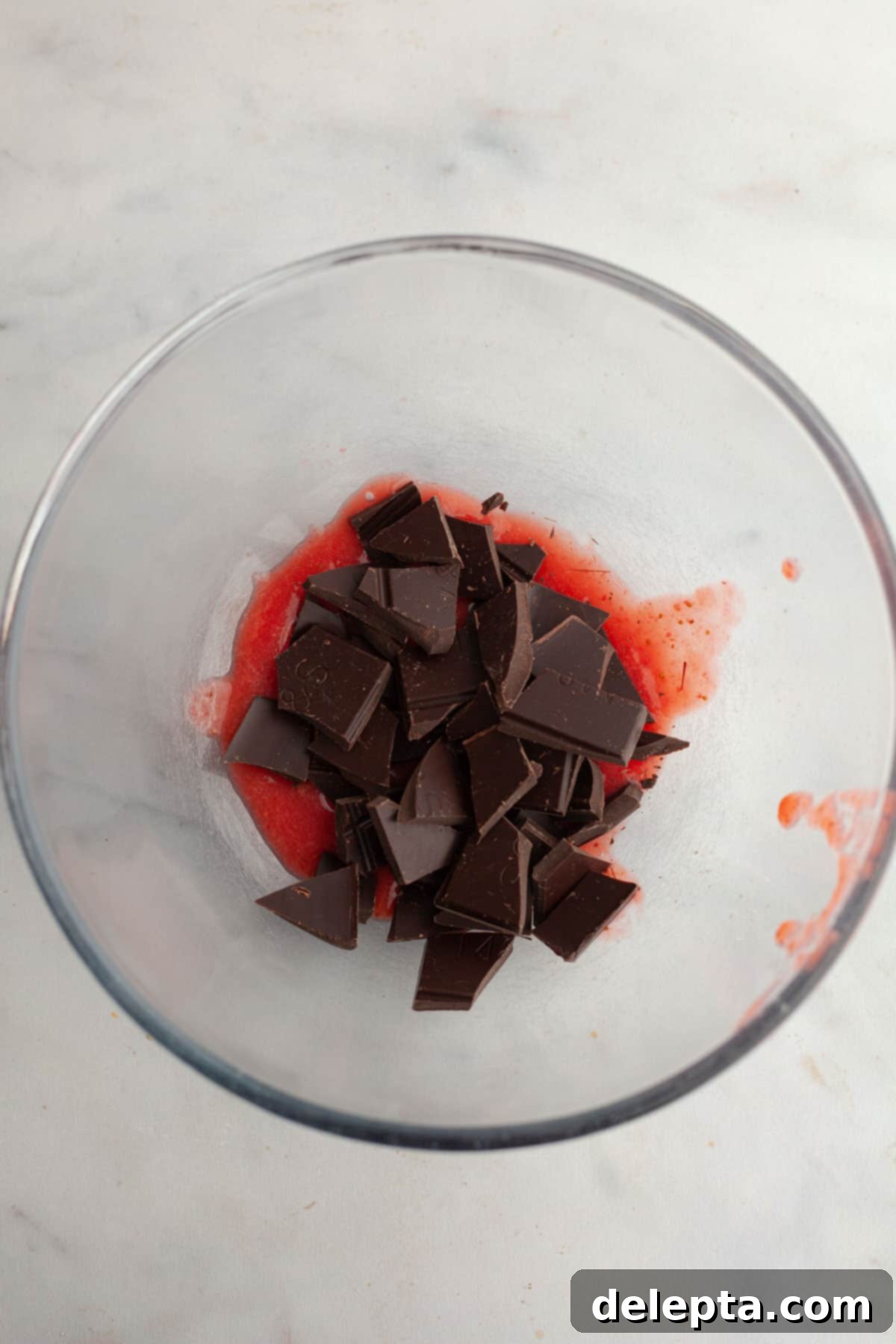 Decadent Chocolate Strawberry Dream Cake 8 Chopped chocolate and strawberry puree in a glass bowl.
