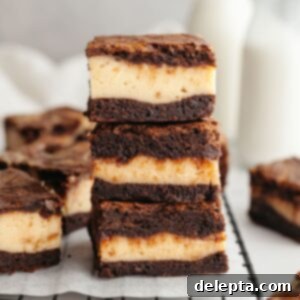 Decadent Peanut Butter Cream Cheese Swirl Brownies 14 A stack of three peanut butter cheesecake brownies on parchment paper, showing the delicious swirl.