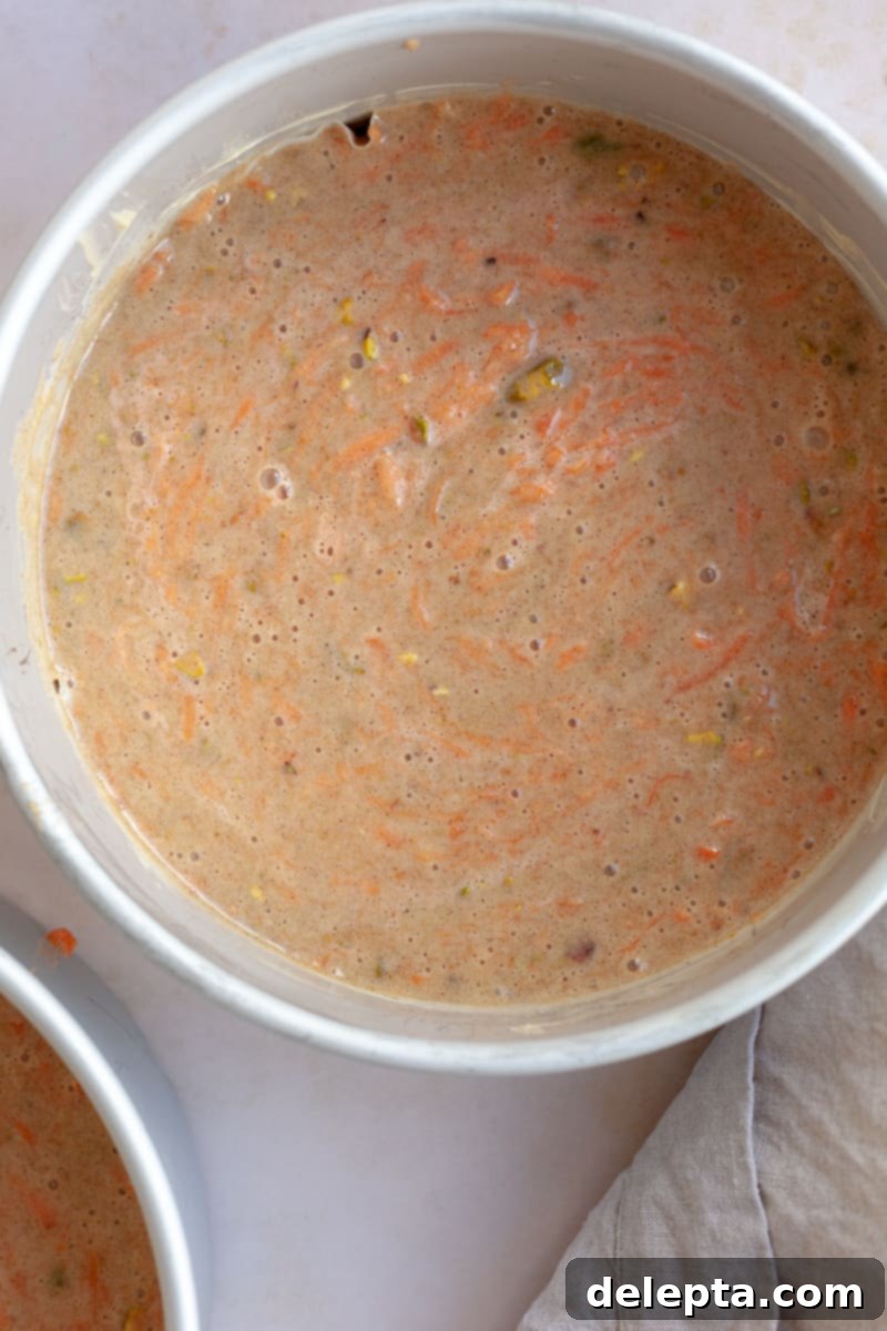 Pistachio-Infused Carrot Cake with Cloud-Like Cream Cheese Frosting 6 Unbaked carrot cake batter in a round cake tin.