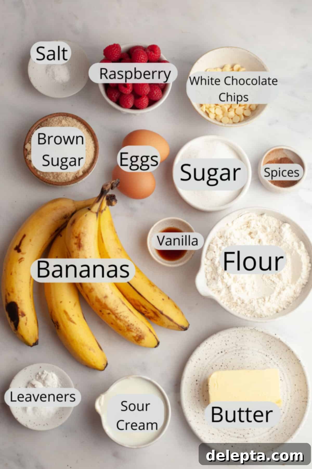 Effortless Banana Raspberry White Chocolate Chip Muffins 3 All the dry and wet ingredients needed to make moist raspberry banana muffins, carefully weighed out into small glass bowls on a kitchen counter.