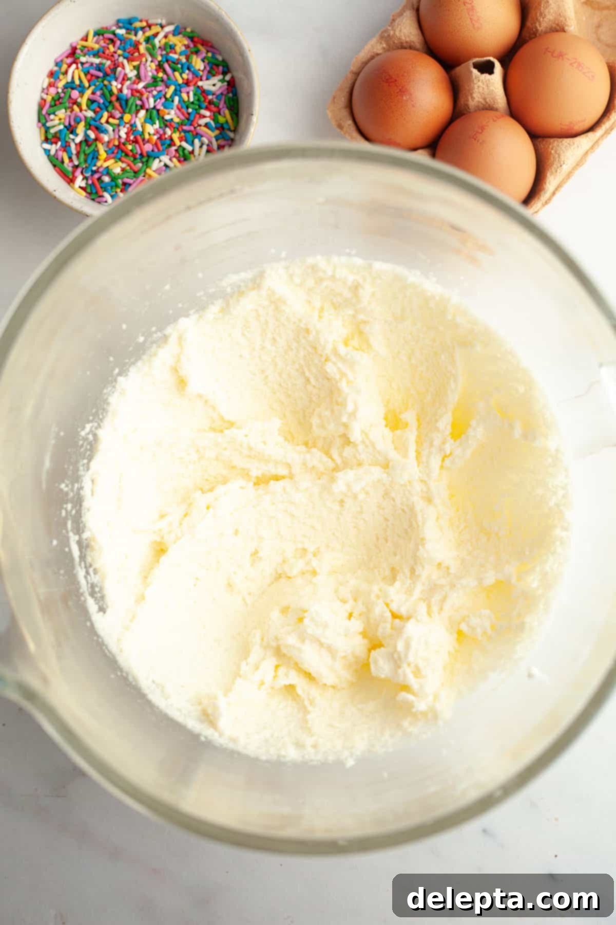 Strawberry Funfetti Fantasy 4 Whipped butter, sugar, and oil in a glass mixing bowl, looking light and fluffy.