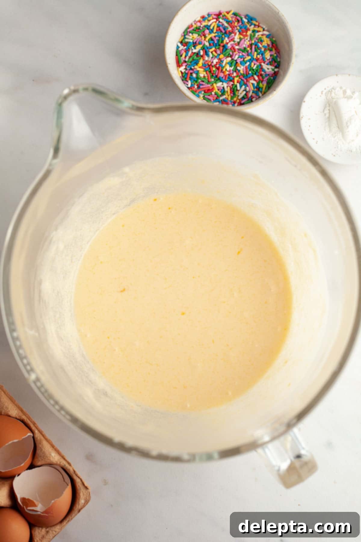 Strawberry Funfetti Fantasy 5 A large glass mixing bowl filled with smooth, pale yellow cake batter.