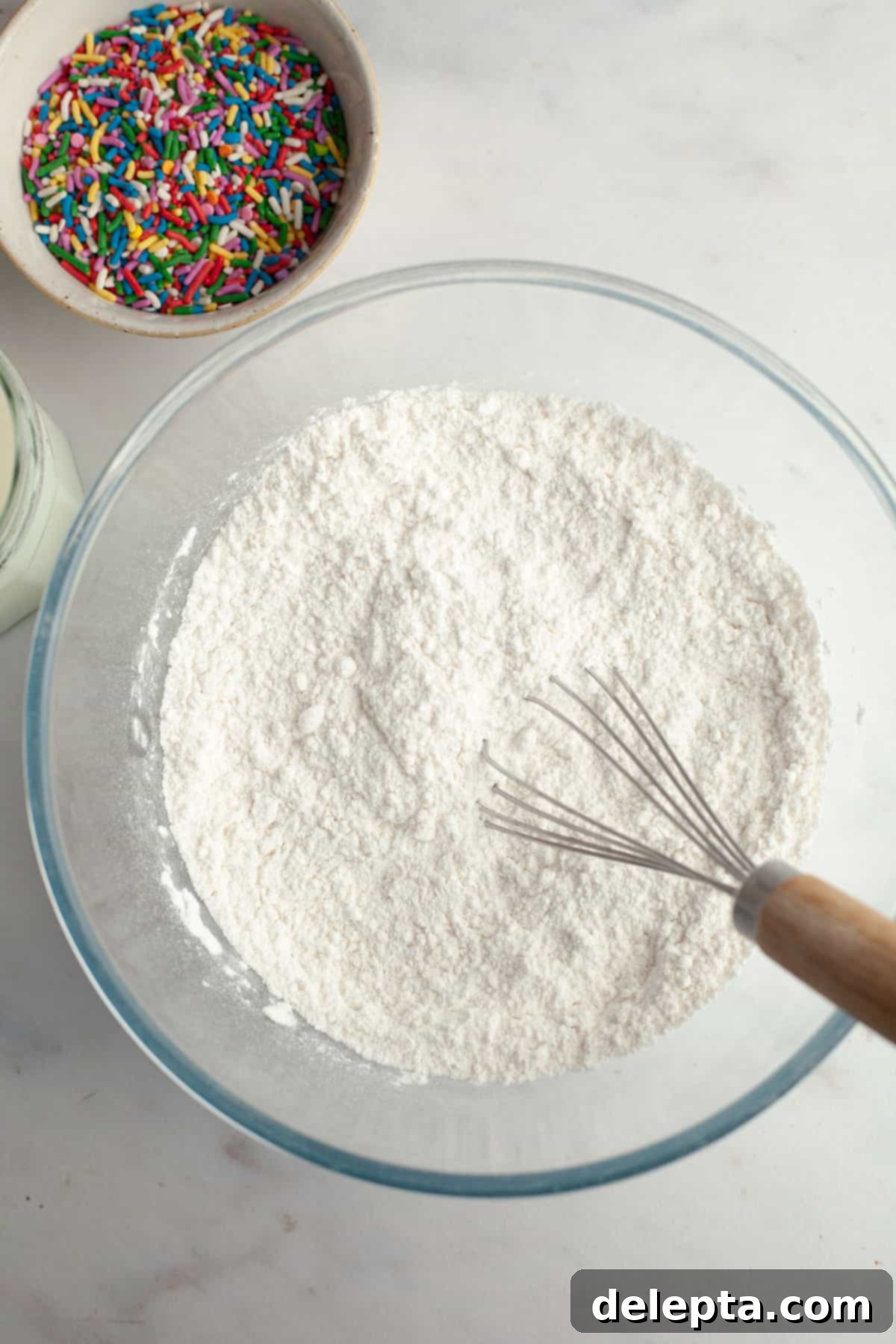 Strawberry Funfetti Fantasy 6 A bowl containing all-purpose flour, baking powder, and kosher salt, mixed with a whisk.