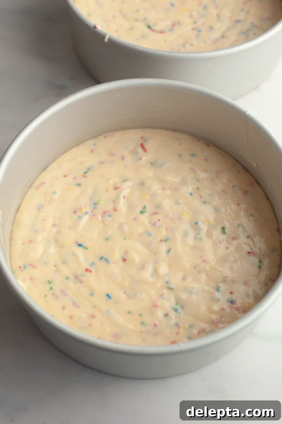 Strawberry Funfetti Fantasy 9 Unbaked funfetti cake batter evenly divided into two round cake pans.