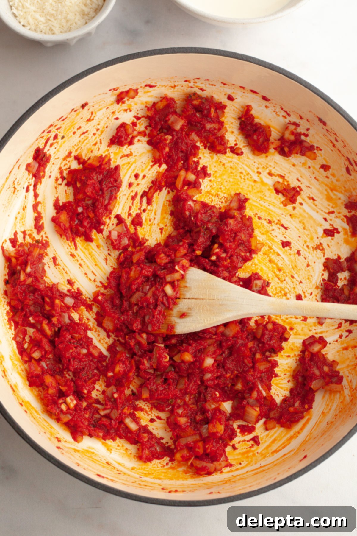 Easy Baked Pasta with Virgin Vodka Sauce 6 A large saucepan with cooked onions, garlic, and tomato paste blending together.