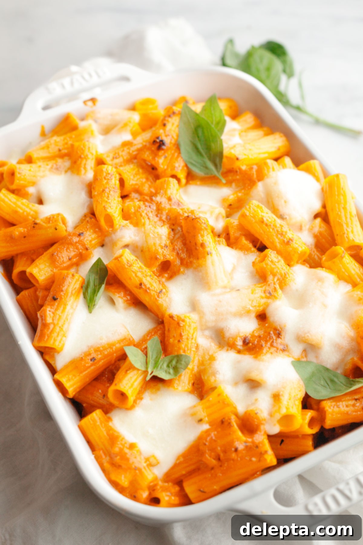 Easy Baked Pasta with Virgin Vodka Sauce 10 A close-up of baked vodka pasta in a white dish, garnished with vibrant green basil leaves.