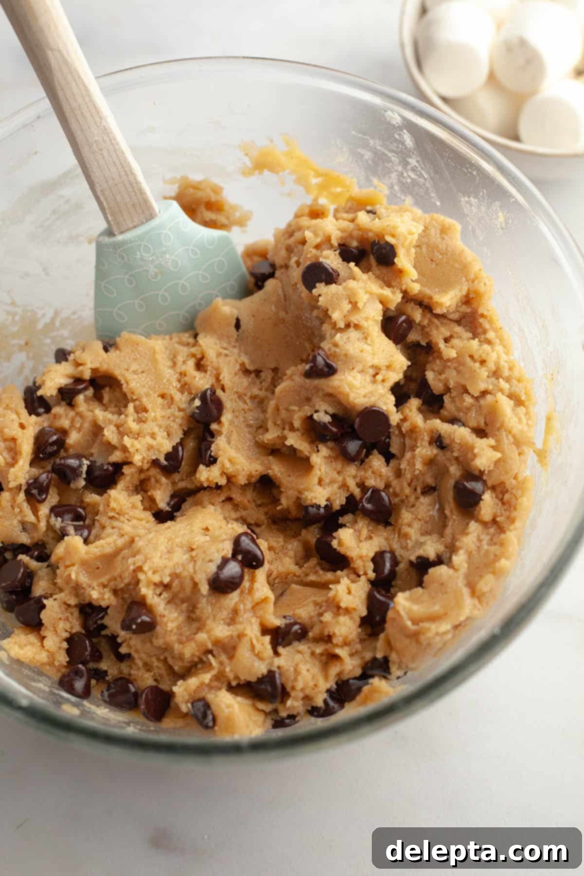 Gooey Chocolate Chip Marshmallow Cookies 6 Classic brown butter chocolate chip cookie dough in a mixing bowl, showcasing its rich texture with chocolate chips folded in.