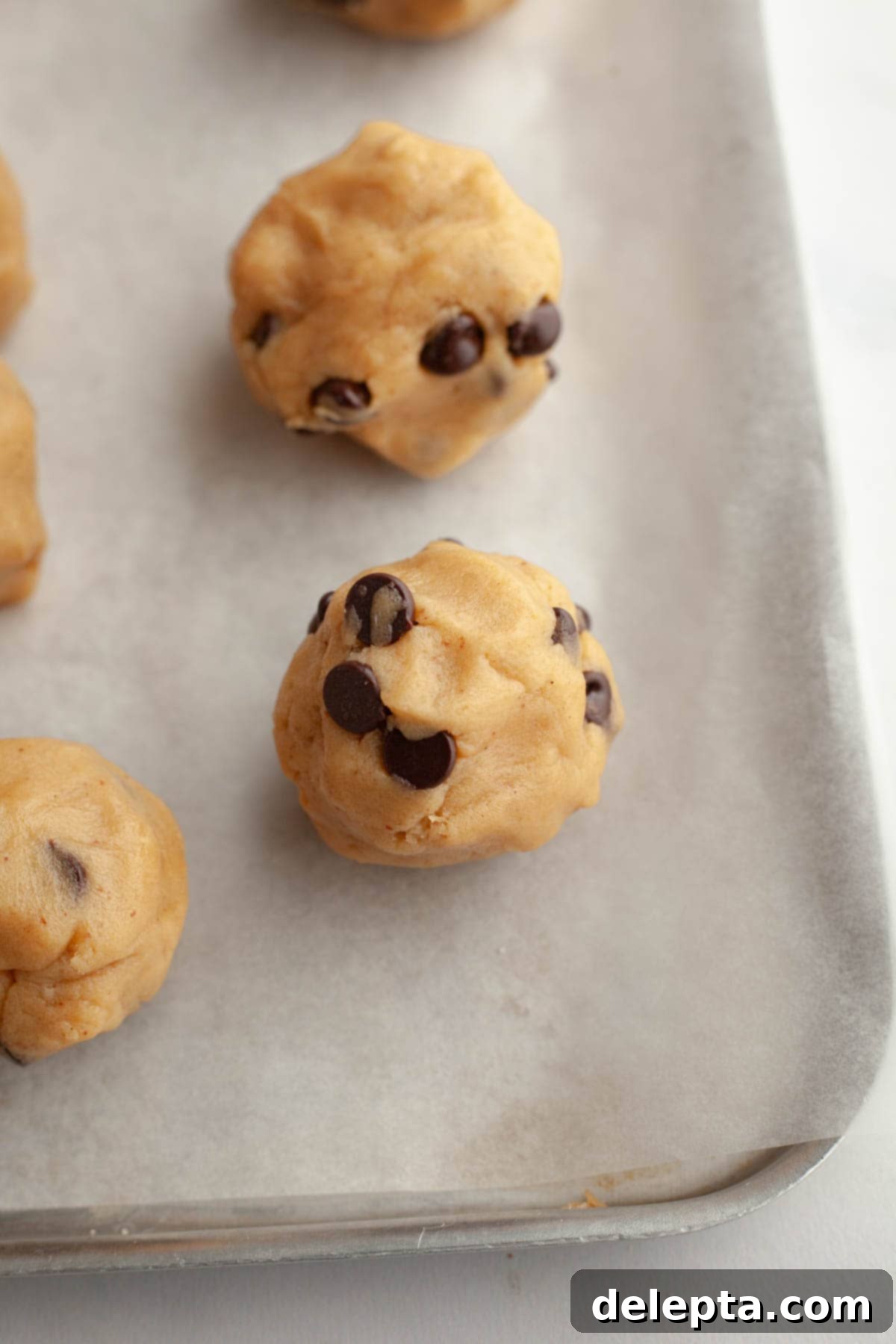 Gooey Chocolate Chip Marshmallow Cookies 9 Perfectly formed brown butter chocolate chip cookie dough balls with marshmallows inside, neatly arranged on parchment paper, ready for baking.