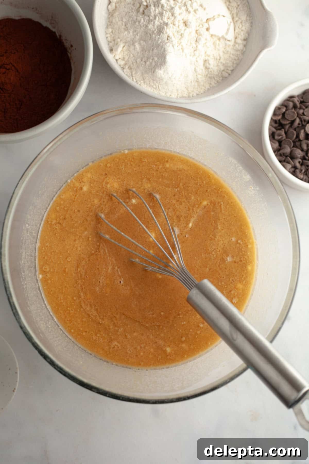Decadent Double Chocolate Espresso Muffins 4 Oil, coffee, eggs, and sour cream mixed together in a glass bowl with a whisk, showing a smooth, creamy mixture.