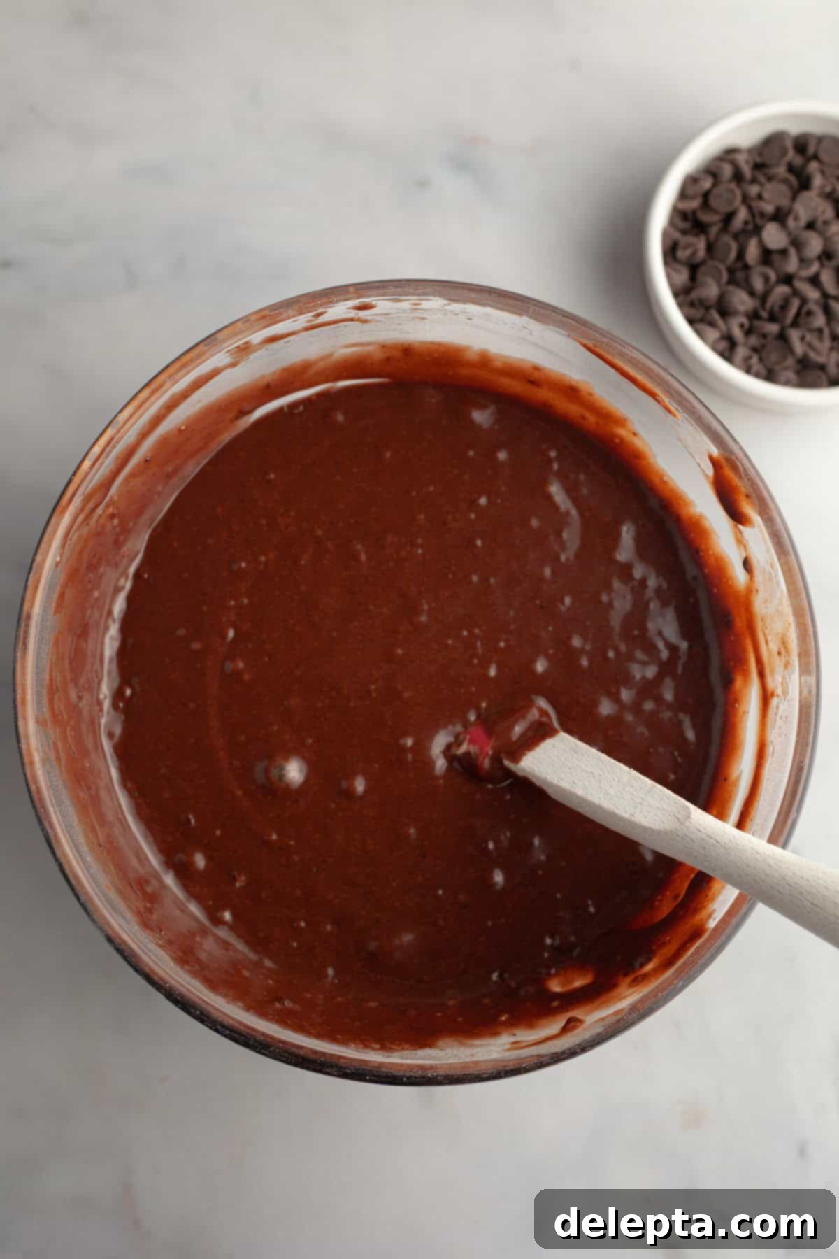 Decadent Double Chocolate Espresso Muffins 5 Chocolate muffin batter in a bowl with a whisk, showing the rich, dark consistency.
