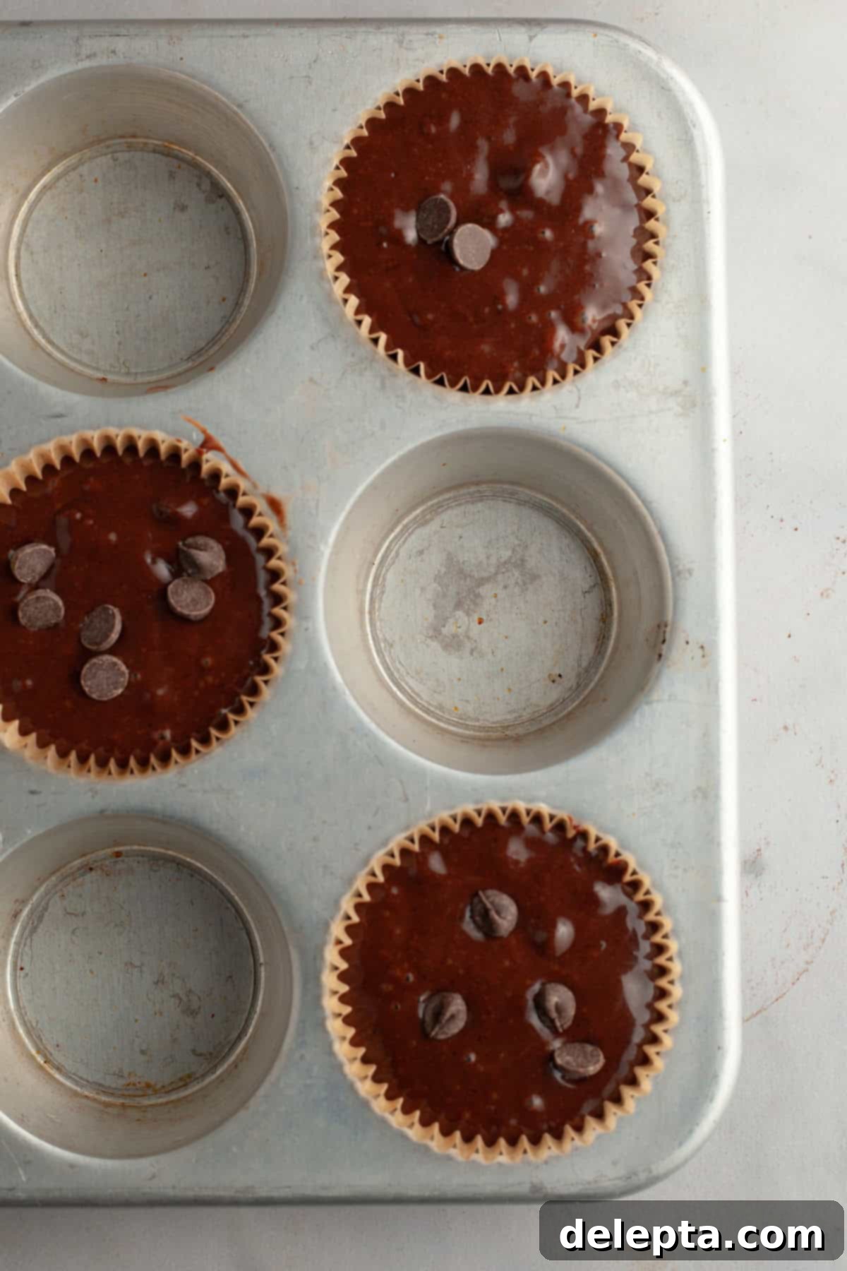Decadent Double Chocolate Espresso Muffins 7 Unbaked chocolate espresso muffins in a muffin pan, showing the technique of lining every other cavity.