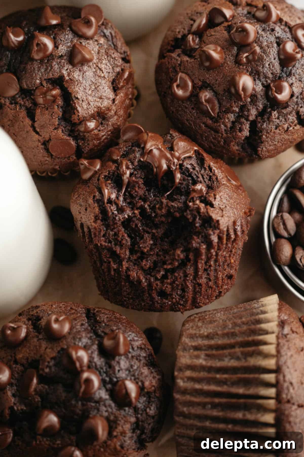 Decadent Double Chocolate Espresso Muffins 9 A close up of double chocolate espresso muffins, one has a bite taken out of it, revealing the moist interior and chocolate chips.