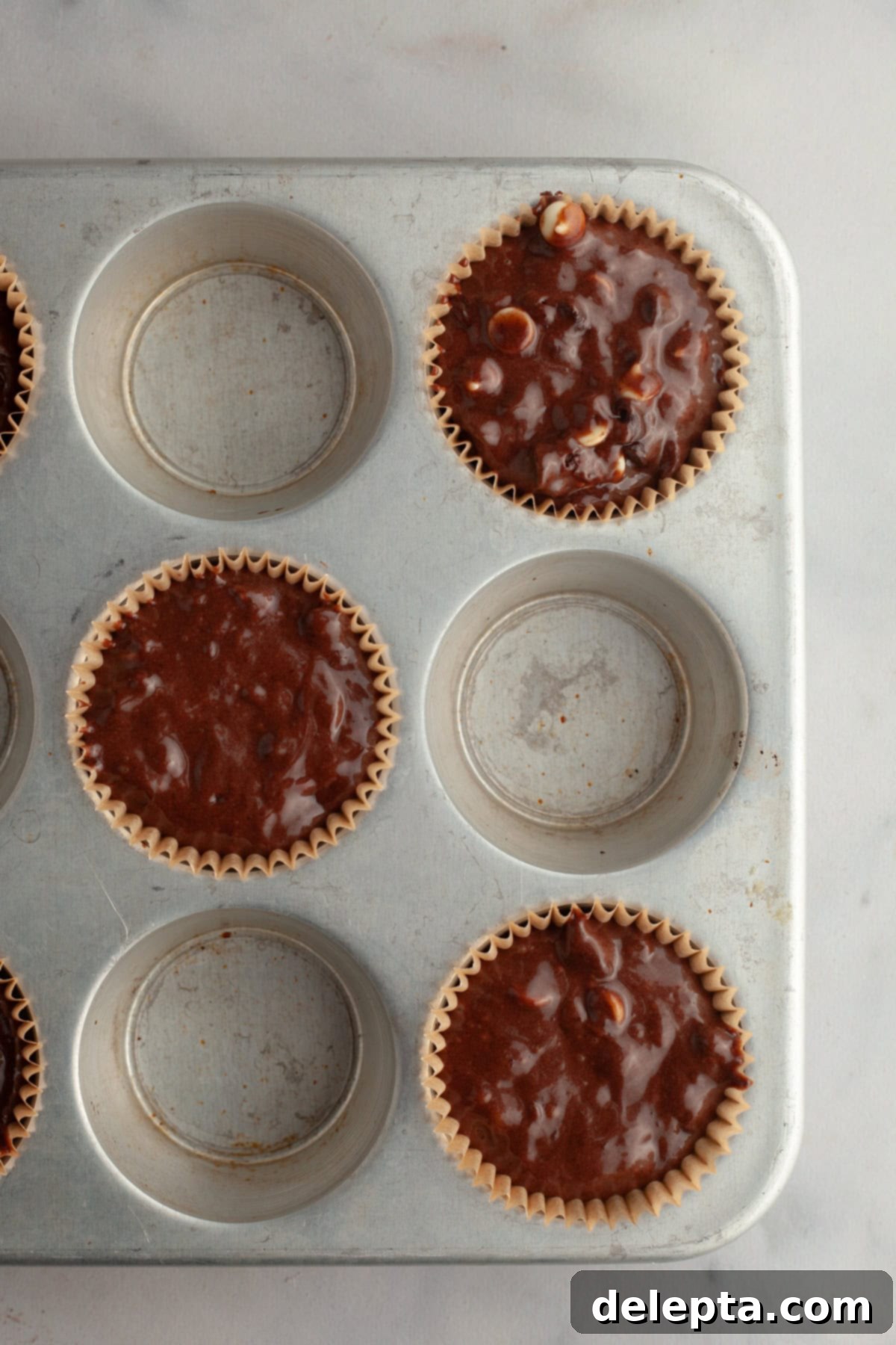 Triple Chocolate Muffins One Bowl Wonder 7 A muffin pan filled with unbaked triple chocolate muffin batter, ready for the oven.