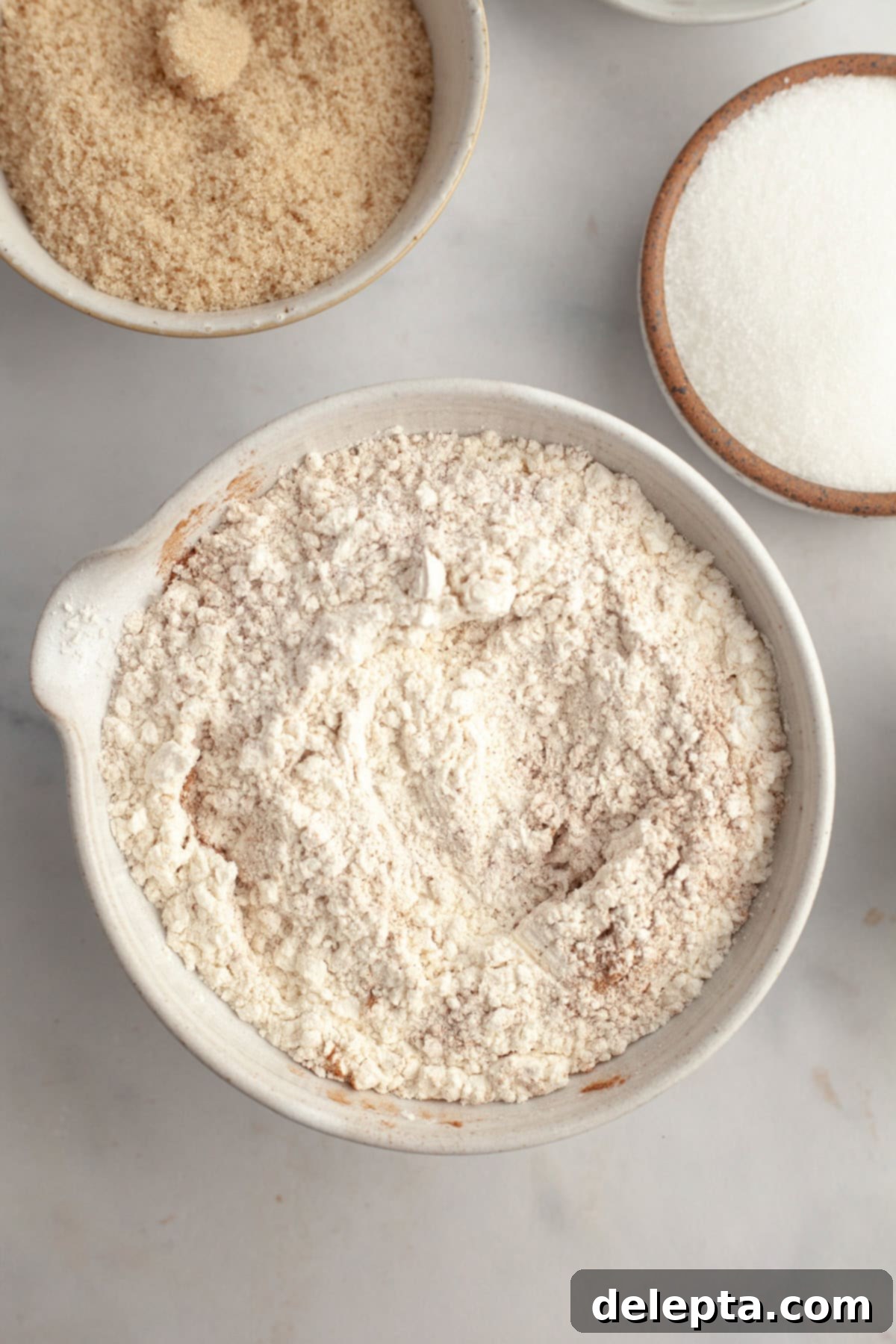Cinnamon Crumble Banana Muffins 4 Flour and cinnamon expertly mixed together in a large bowl, forming the dry ingredients for the muffin batter.