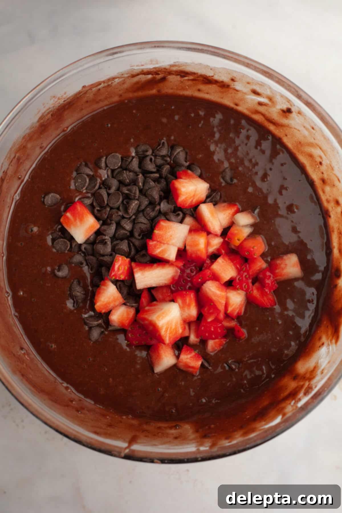 Decadent Double Chocolate Strawberry Muffins 6 Chocolate muffin batter in a bowl with chocolate chips and chopped up strawberries, ready for resting.