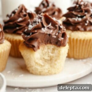 Double Chocolate Coconut Indulgence 12 A close up of a coconut cupcake with chocolate frosting with a bite taken out of it.