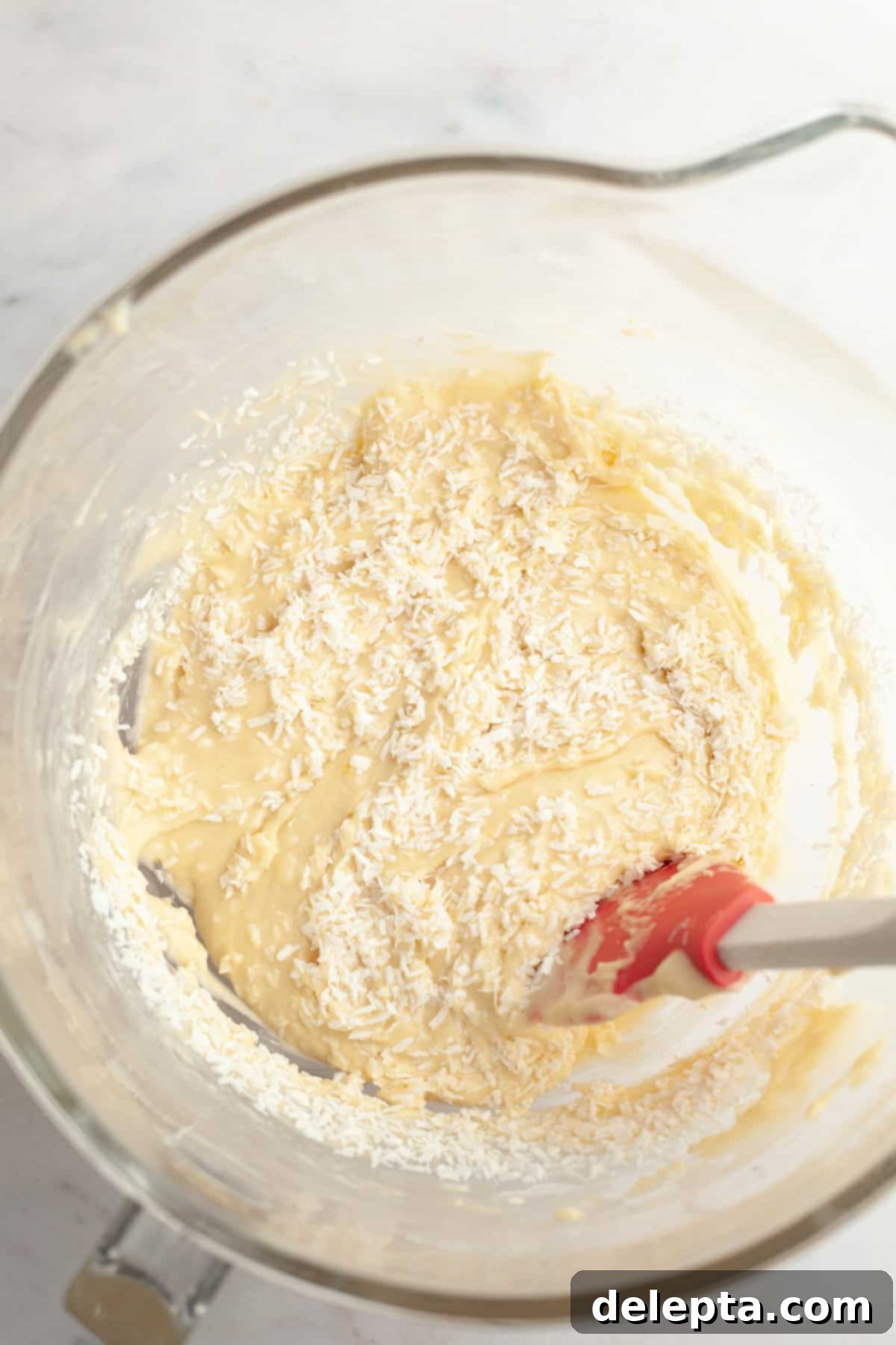 Double Chocolate Coconut Indulgence 7 A yellow cupcake batter with shredded coconut in a glass mixing bowl.