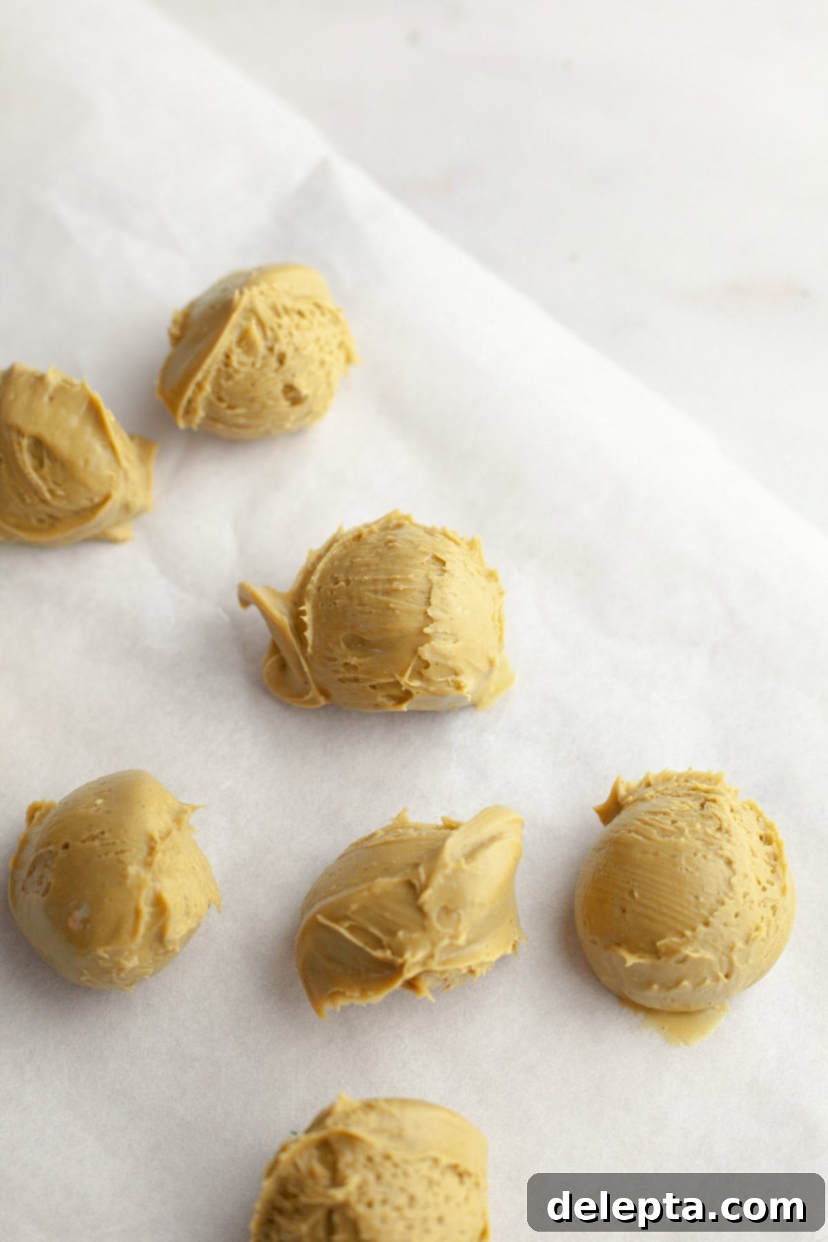 Pistachio Stuffed Chocolate Chip Delights 4 Scooped out balls of chilled pistachio cream arranged neatly on parchment paper, ready for freezing to solidify.