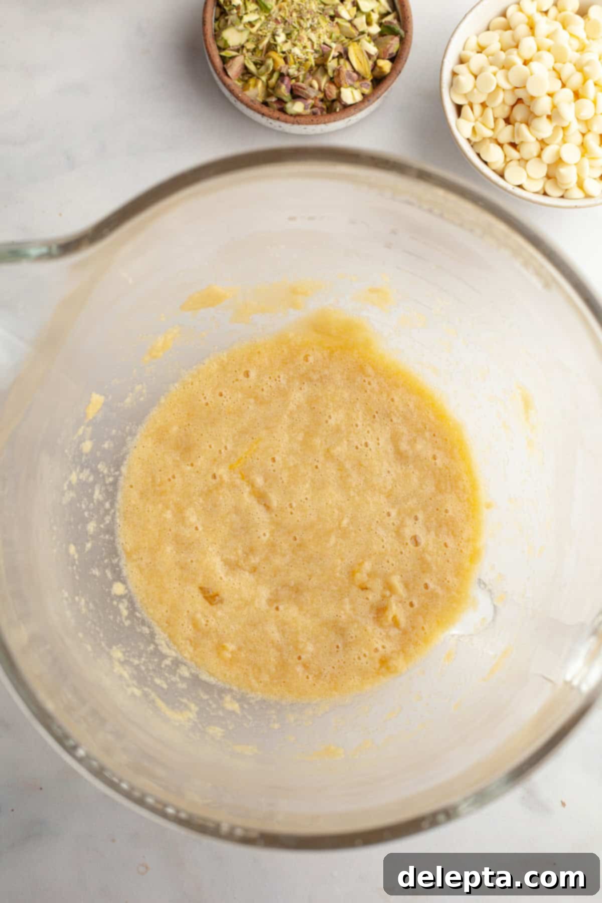 Pistachio Stuffed Chocolate Chip Delights 5 A glass mixing bowl containing a light yellow, fluffy butter and sugar mixture, beaten until aerated and pale.