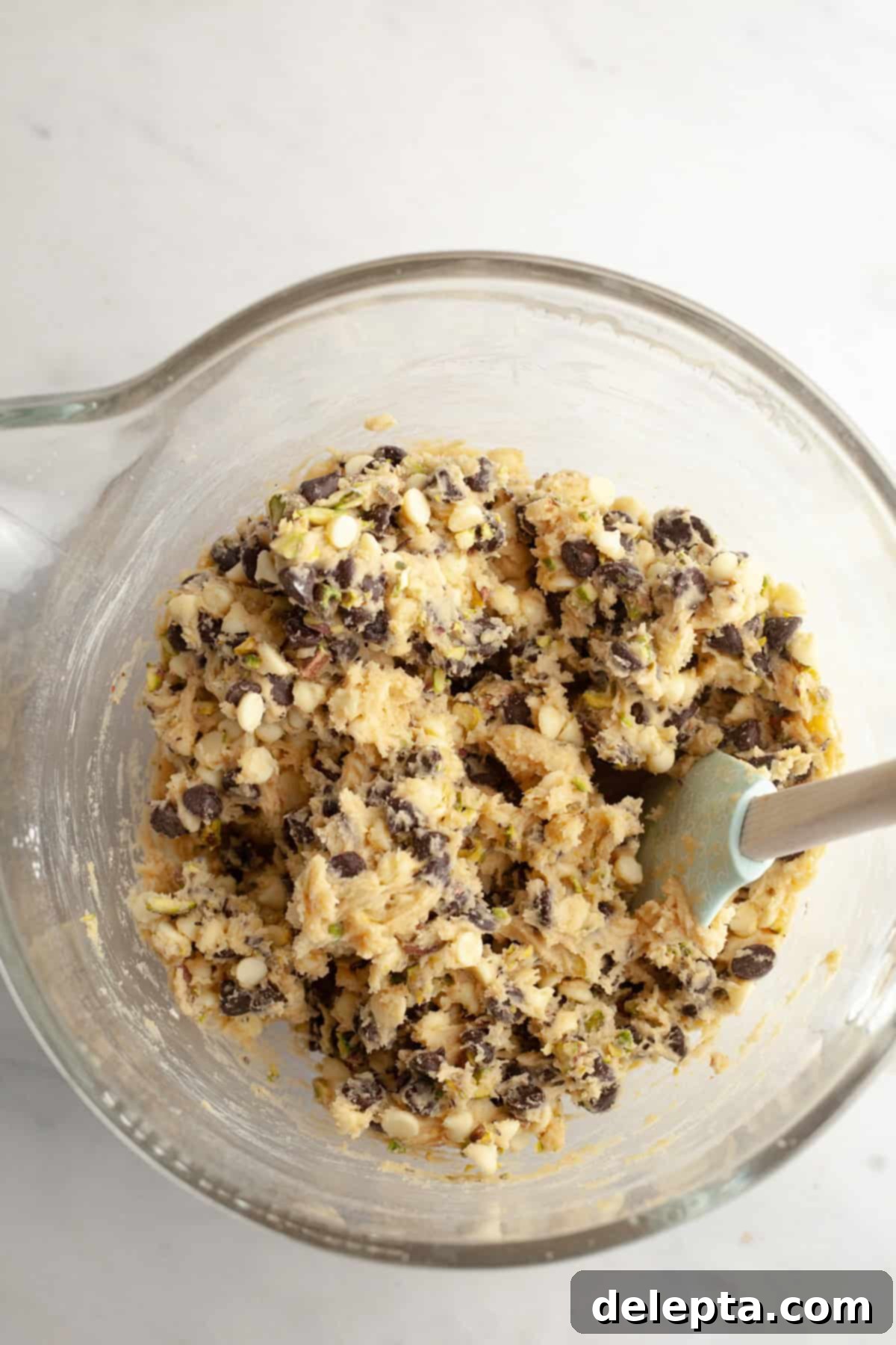 Pistachio Stuffed Chocolate Chip Delights 7 A mixing bowl filled with vibrant pistachio chocolate chip cookie dough, showcasing the colorful mix-ins of chocolate chips and chopped pistachios.