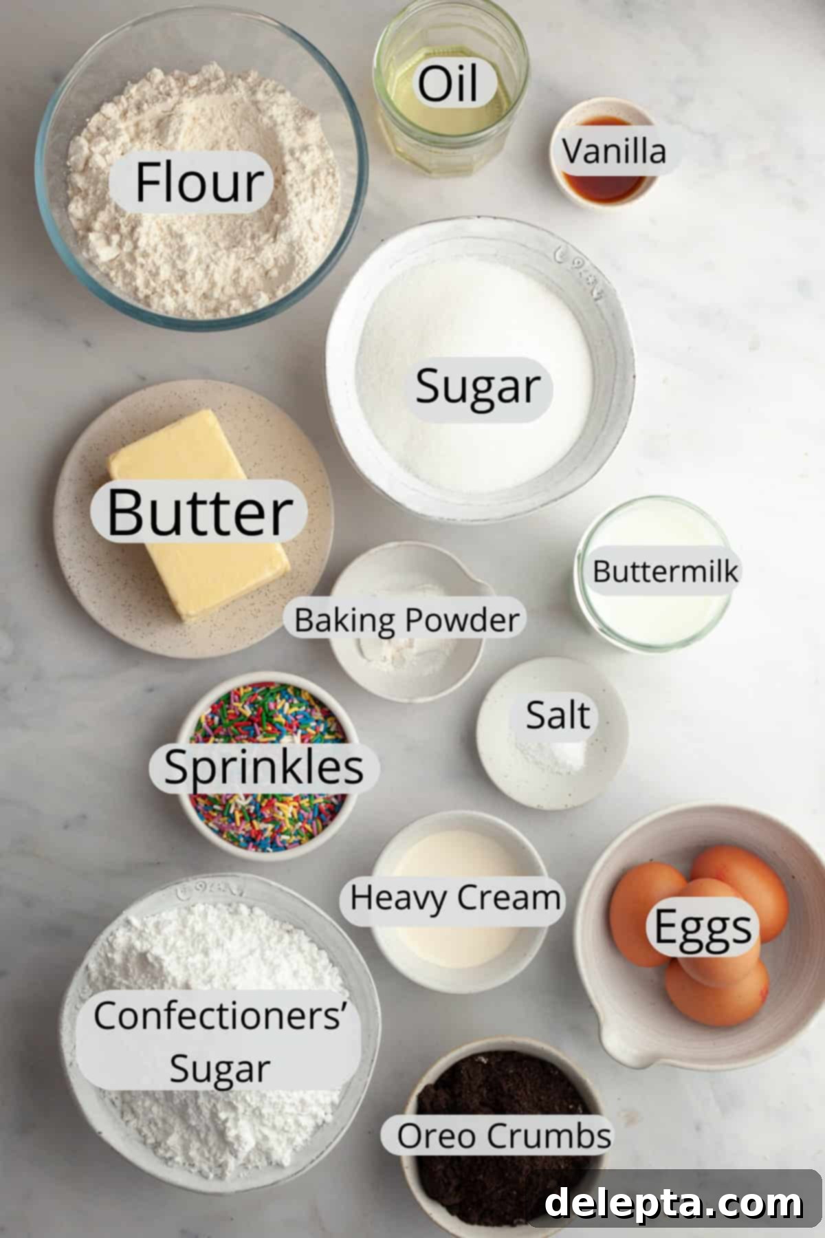 Simply Delicious Funfetti Oreo Cake with Dreamy Oreo Frosting 3 A collection of ingredients for funfetti Oreo cake, neatly portioned into small bowls on a wooden surface.
