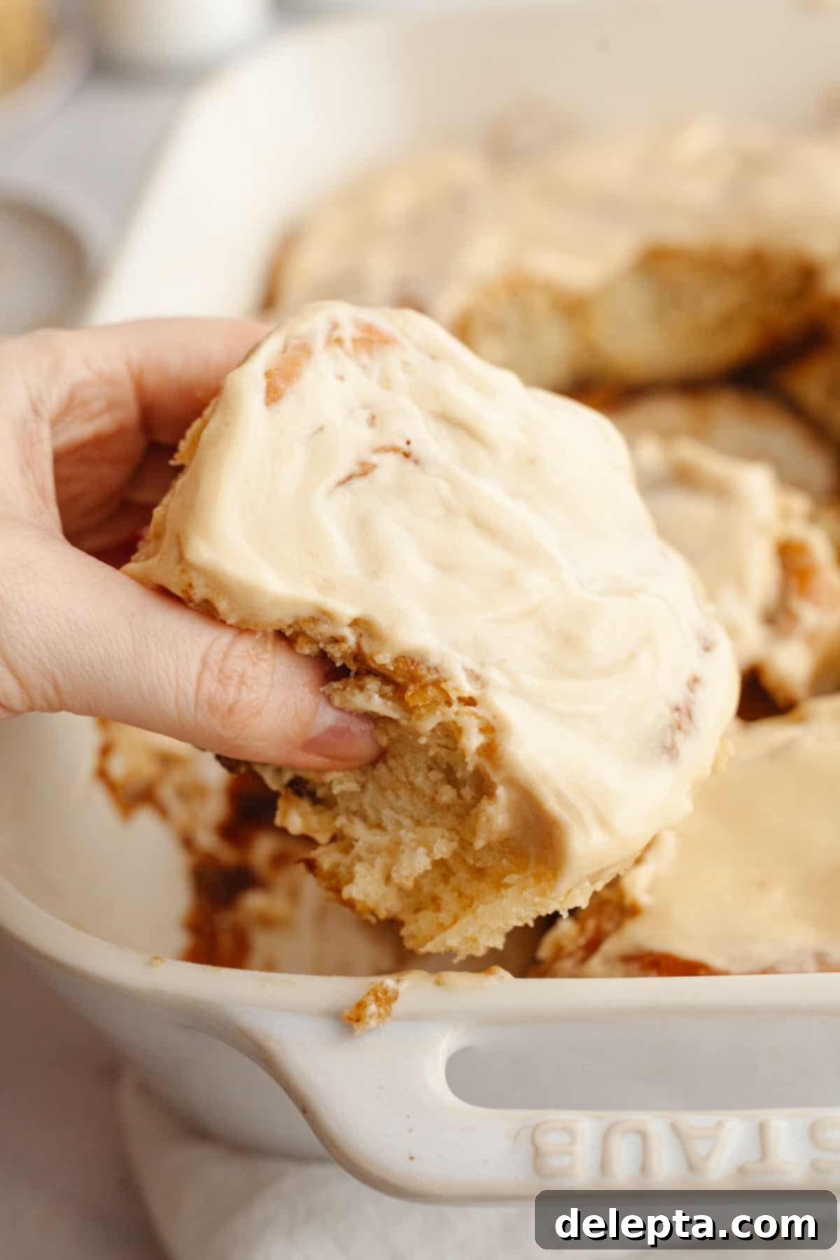 Maple Espresso Cinnamon Swirls 2 A hand grabbing a cinnamon coffee roll with maple espresso icing.