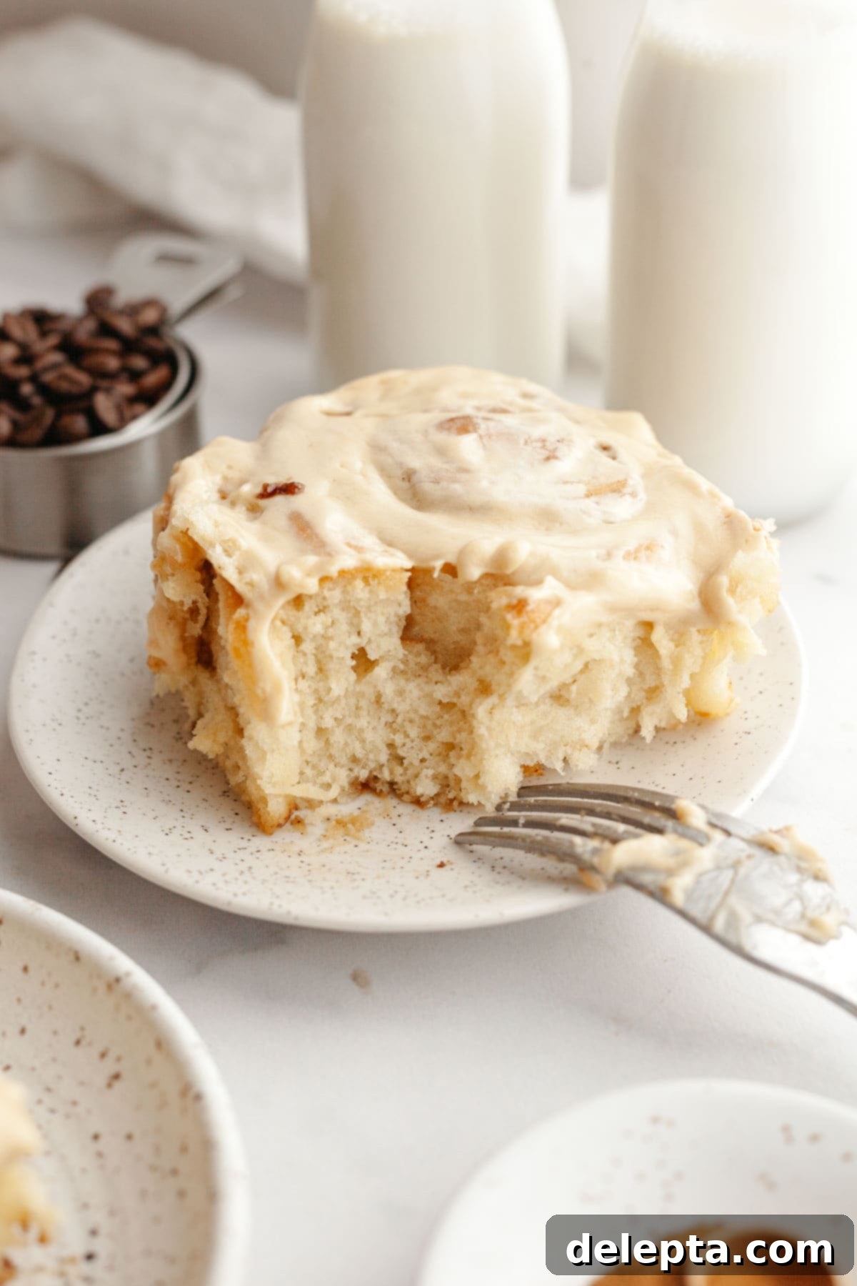 Maple Espresso Cinnamon Swirls 13 A cinnamon coffee roll with maple espresso icing on a plate.