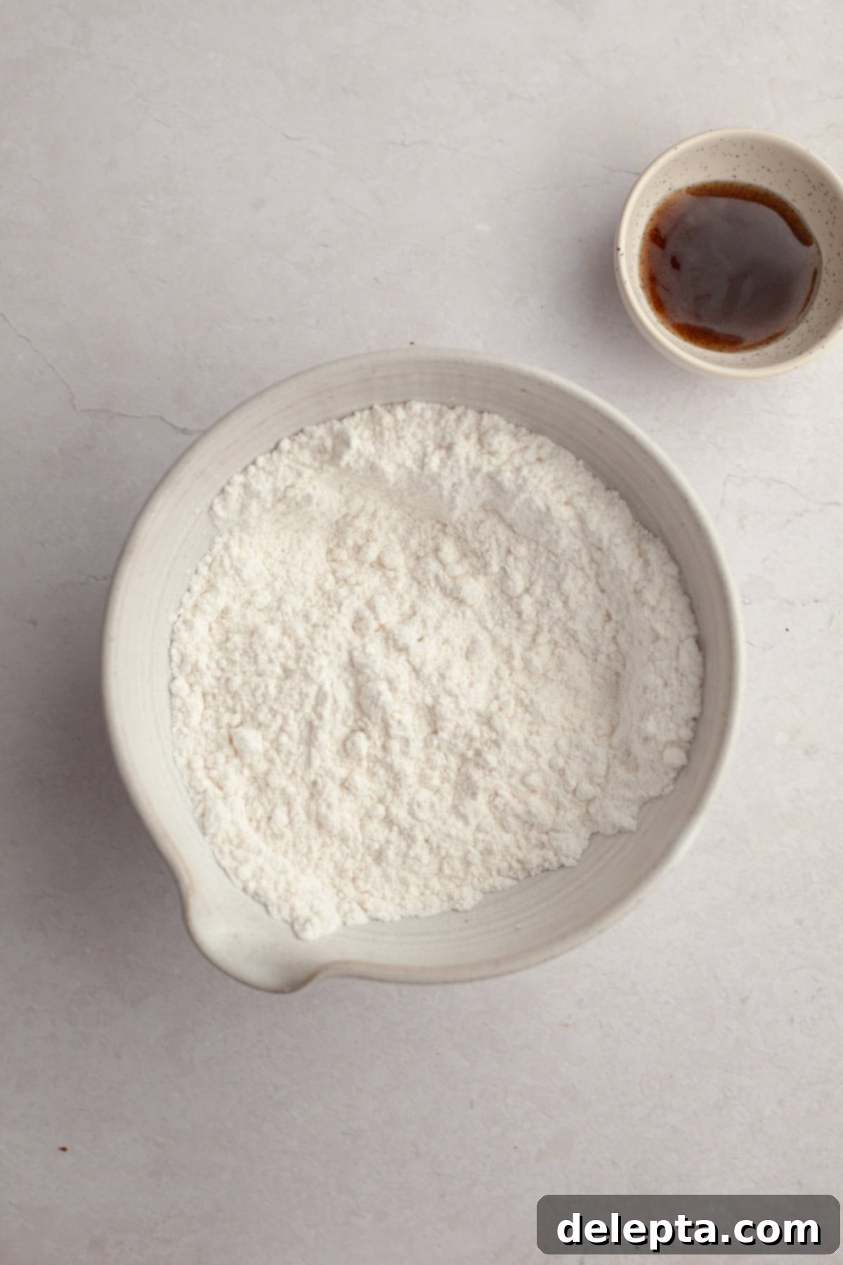 Pure Vanilla Bean Bliss Cupcakes 4 A crisp white bowl filled with precisely measured cake flour, ready for mixing.