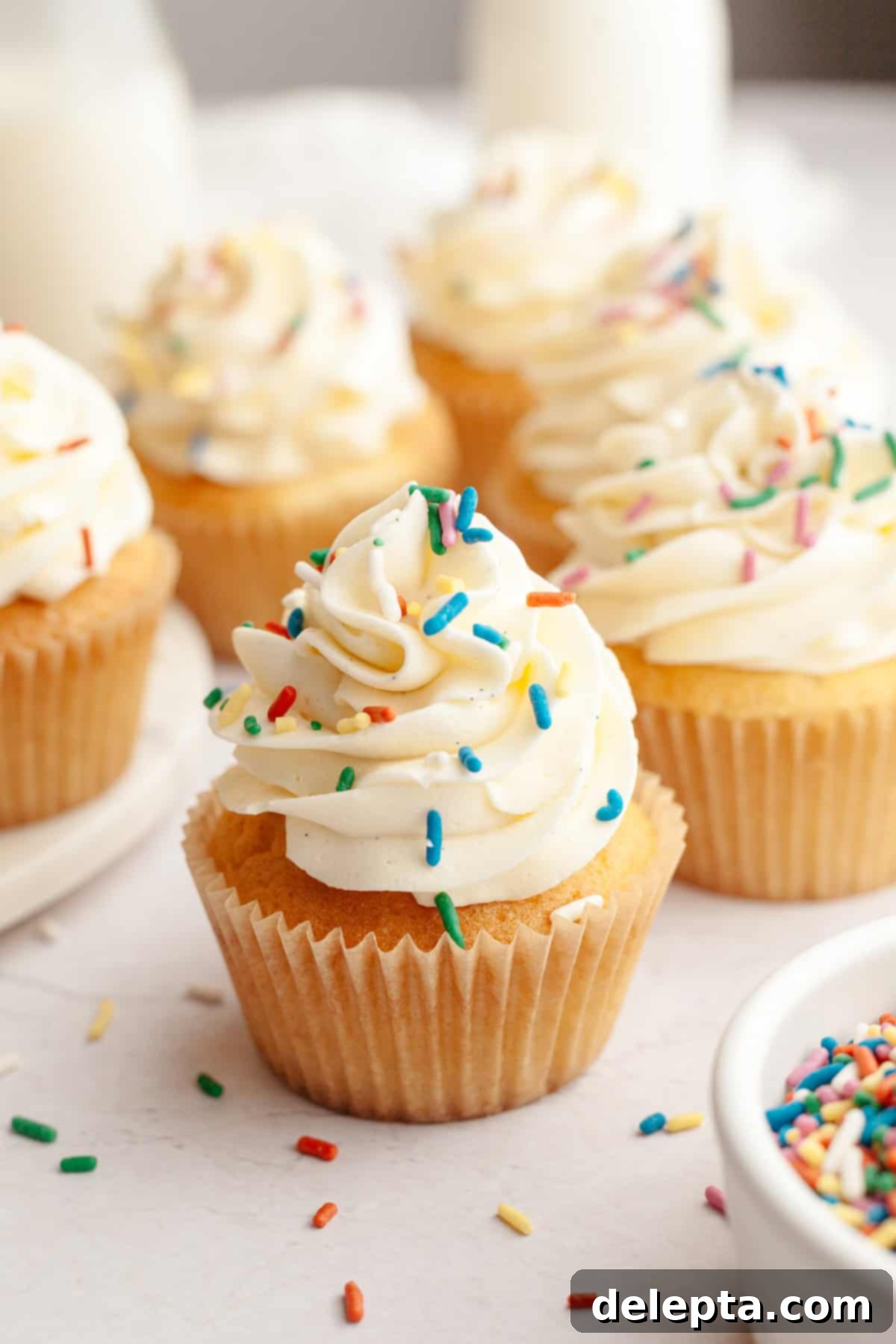 Pure Vanilla Bean Bliss Cupcakes 9 A close-up view of beautifully frosted vanilla bean cupcakes, each topped with a generous swirl of buttercream and a scattering of rainbow sprinkles.