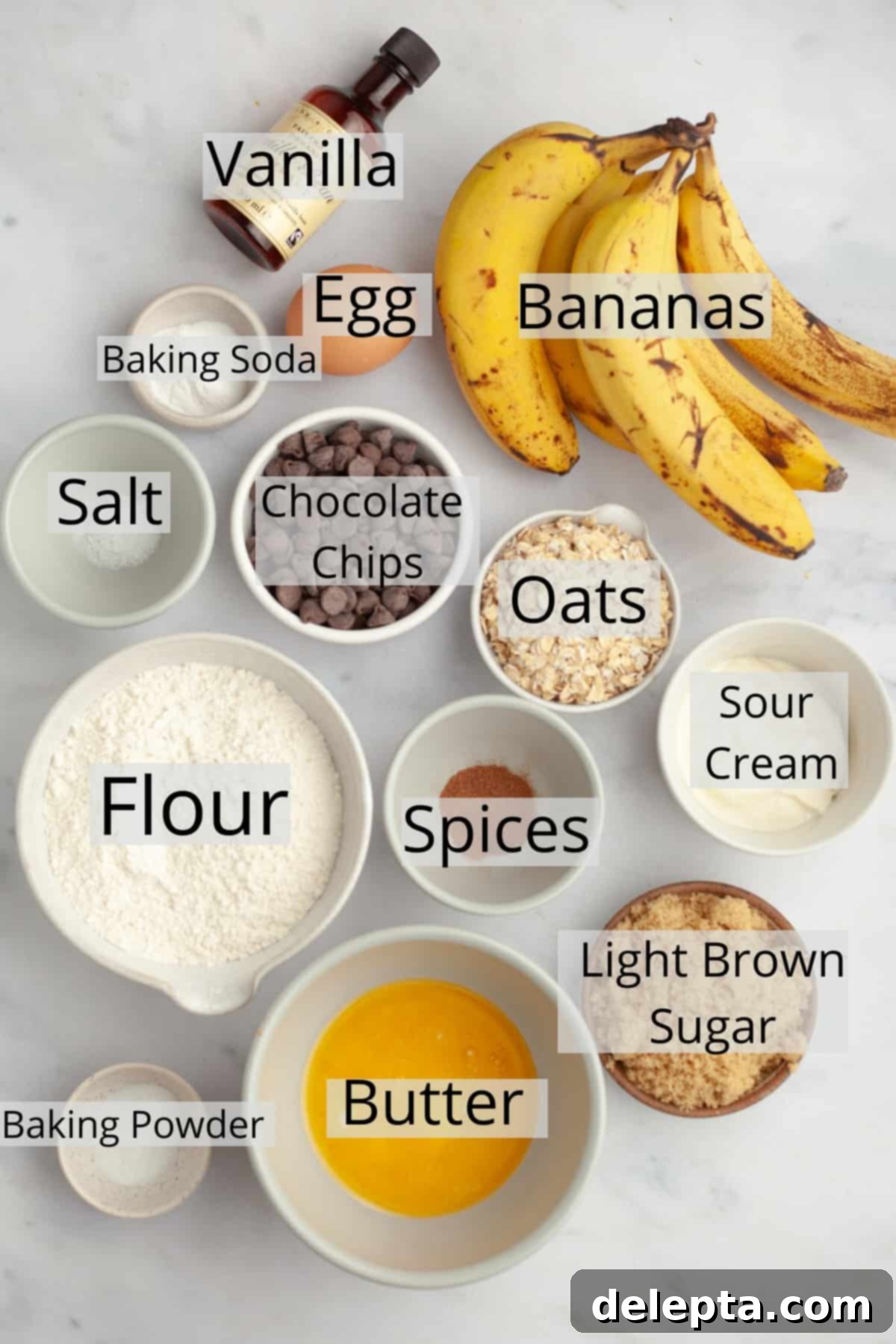 Wholesome Banana Oat Chocolate Chip Muffins 3 A collection of fresh ingredients laid out on a table, including flour, ripe bananas, oats, sour cream, and chocolate chips, all ready to be used for baking oatmeal banana chocolate chip muffins.