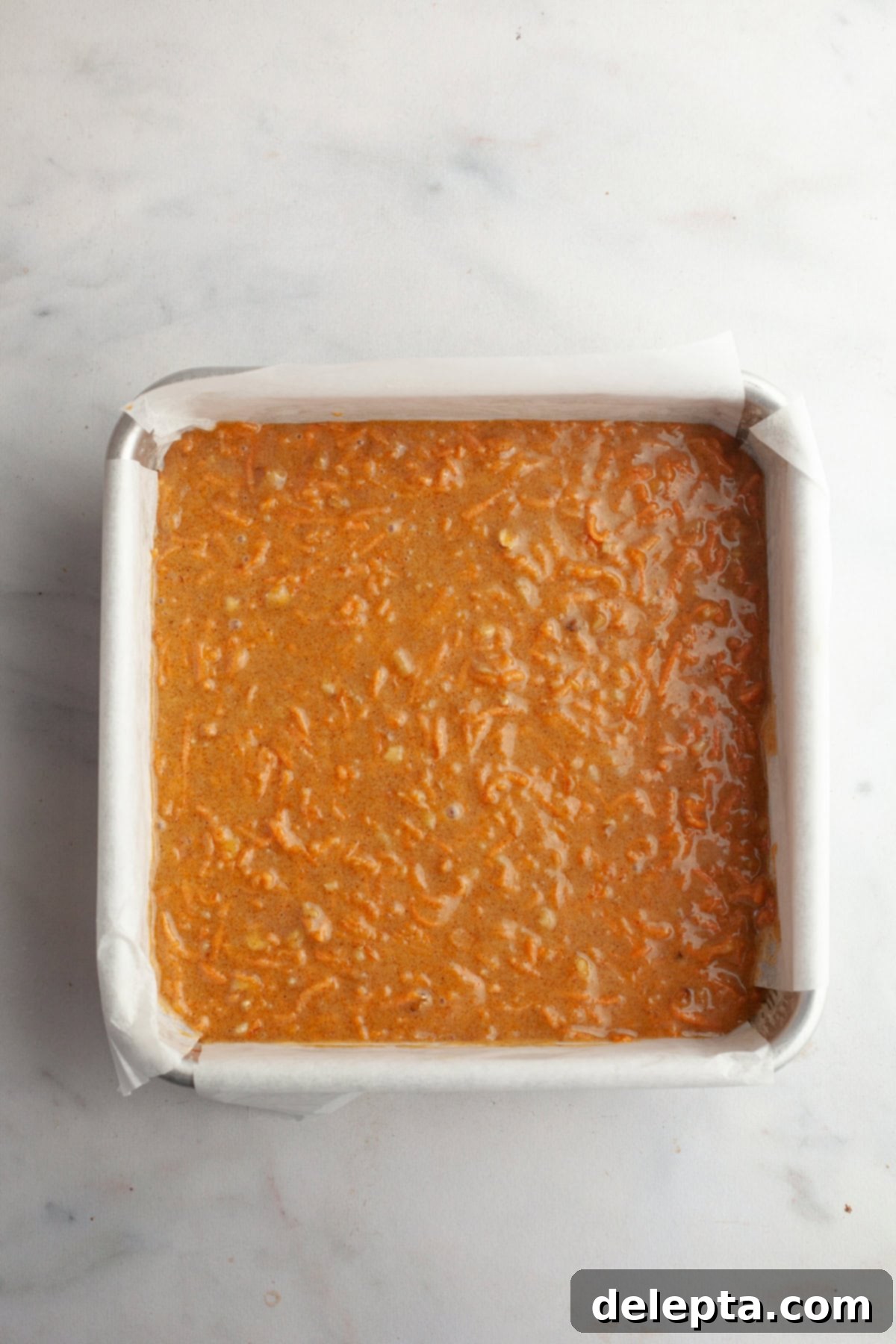 Butter-Free Mini Carrot Cake with Dreamy Cream Cheese Frosting 6 Unbaked carrot cake in a square pan.