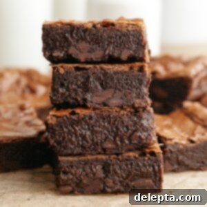 Decadent One Bowl Fudgy Brown Butter Espresso Brownies 11 A stack of four brown butter espresso brownies on parchment paper, perfectly sliced and ready to enjoy.